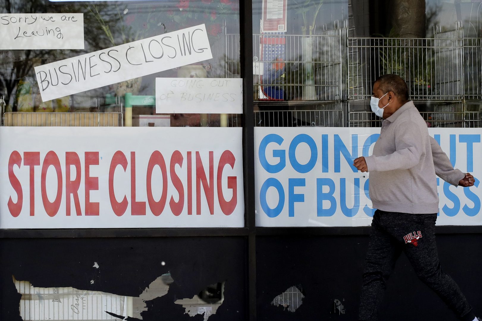 FILE - In this May 21, 2020 file photo, a man looks at signs of a closed store due to COVID-19 in Niles, Ill.   