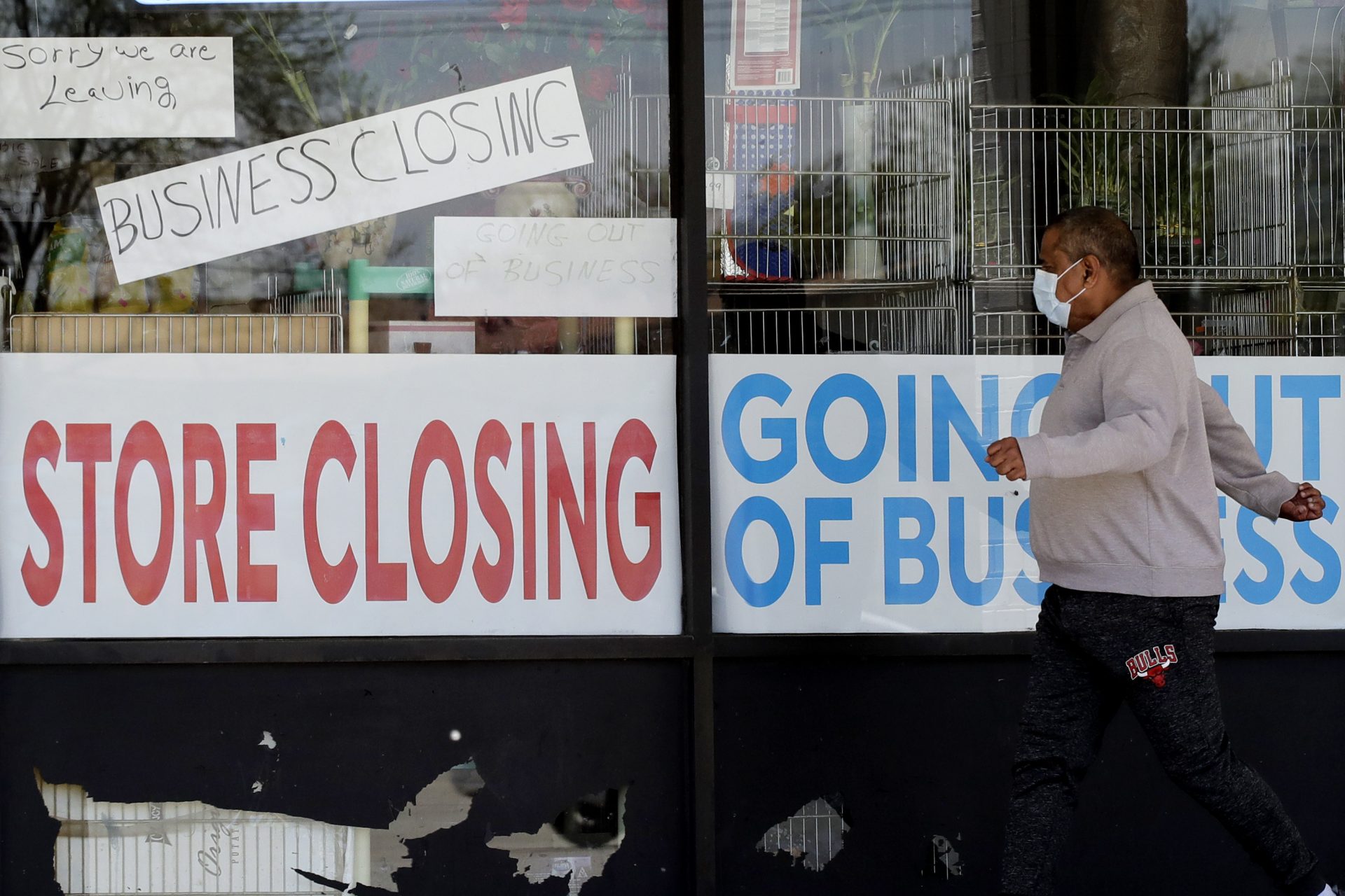 FILE - In this May 21, 2020 file photo, a man looks at signs of a closed store due to COVID-19 in Niles, Ill. U.S. businesses shed 2.76 million jobs in May, as the economic damage from the historically unrivaled coronavirus outbreak stretched into a third month. The payroll company ADP reported Wednesday that businesses have let go of a combined 22.6 million jobs since March.