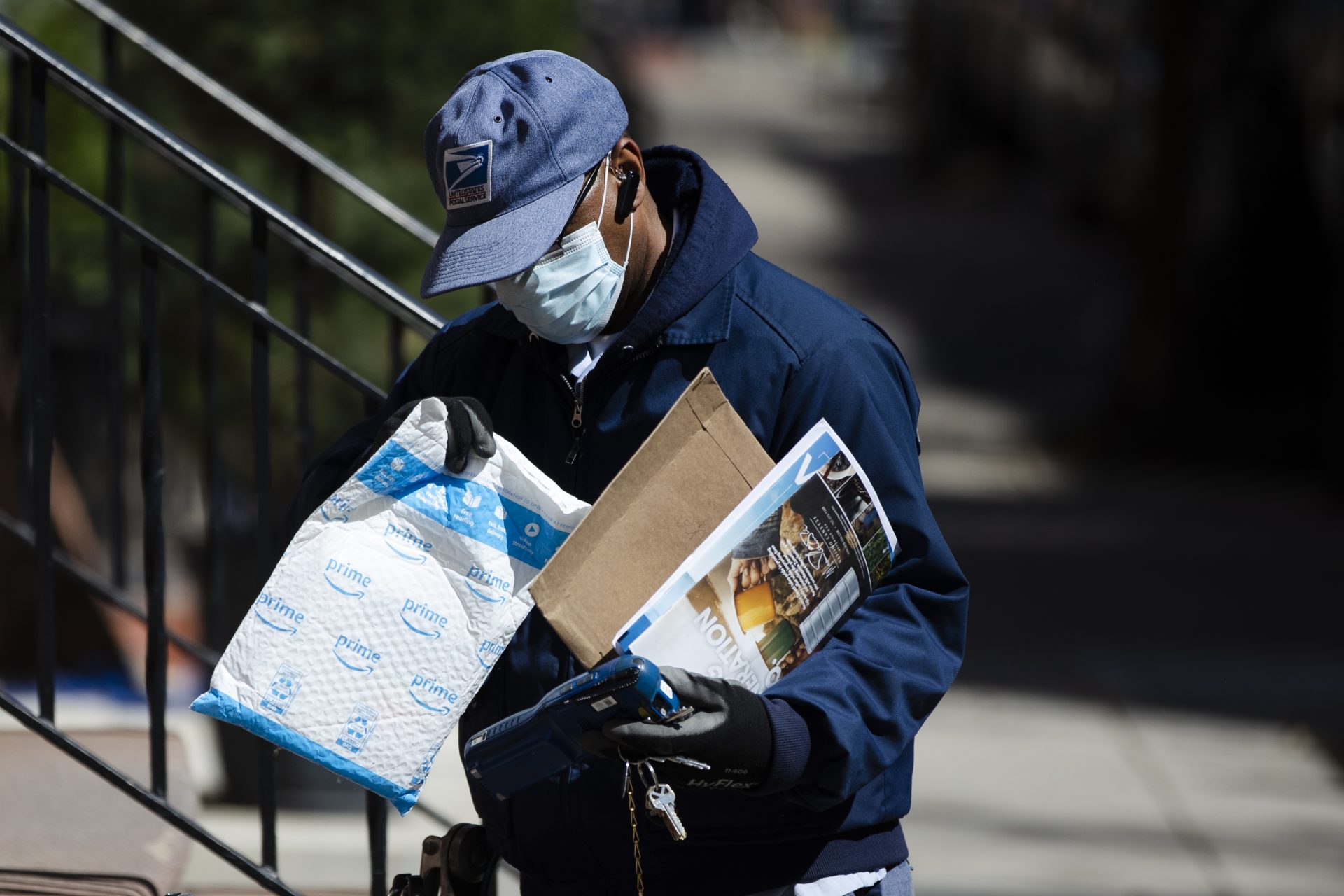 A United States Postal worker makes a delivery with gloves and a mask in Philadelphia, Thursday, April 2, 2020.