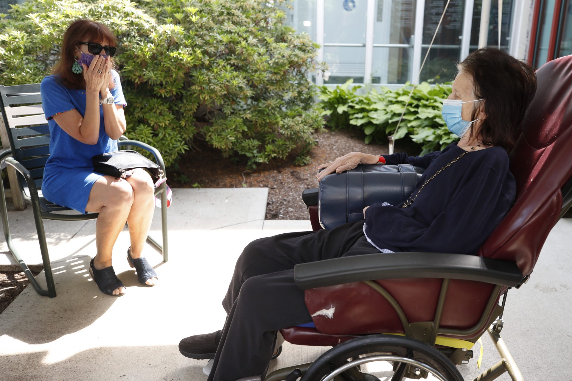 Marcie Abramson, left, becomes emotional as she speaks to her mother, Cynthia, outdoors at the Hebrew Rehabilitation Center, Wednesday June 10, 2020, in Boston, under the state's new nursing home visitation guidelines which requires social distancing. The two haven't been able to visit in person since March.
