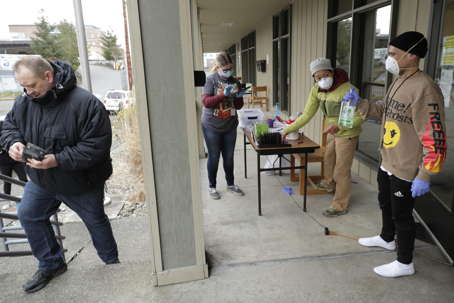 In this March 27, 2020 photo, Garrett McIntyre, left, arrives to pick up medication for opioid addiction at a clinic in Olympia, Wash., that is currently meeting patients outdoors and offering longer prescriptions in hopes of reducing the number of visits and the risk of infection due to the outbreak of the new coronavirus.
