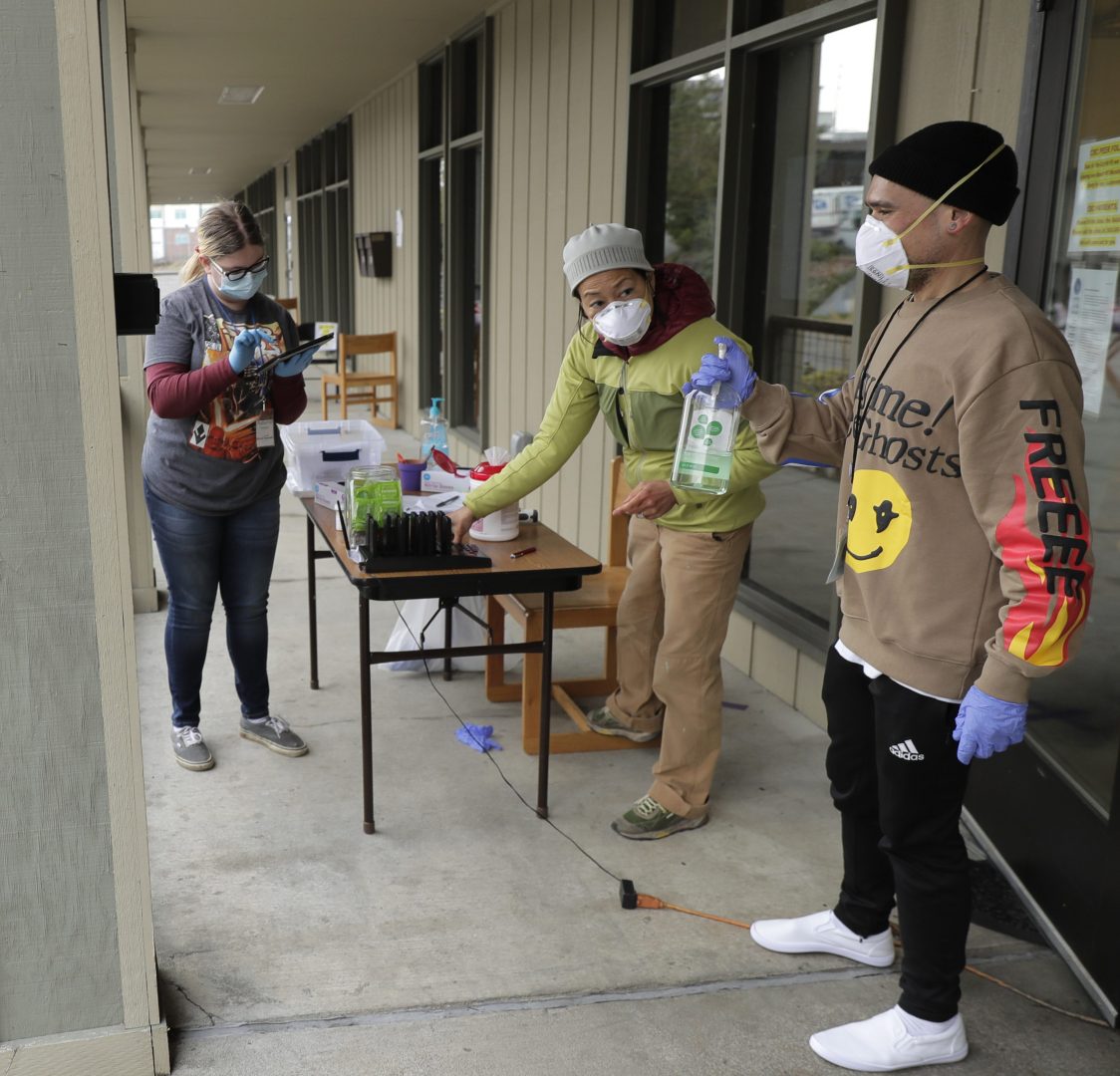 In this March 27, 2020 photo, Garrett McIntyre, left, arrives to pick up medication for opioid addiction at a clinic in Olympia, Wash., that is currently meeting patients outdoors and offering longer prescriptions in hopes of reducing the number of visits and the risk of infection due to the outbreak of the new coronavirus. 