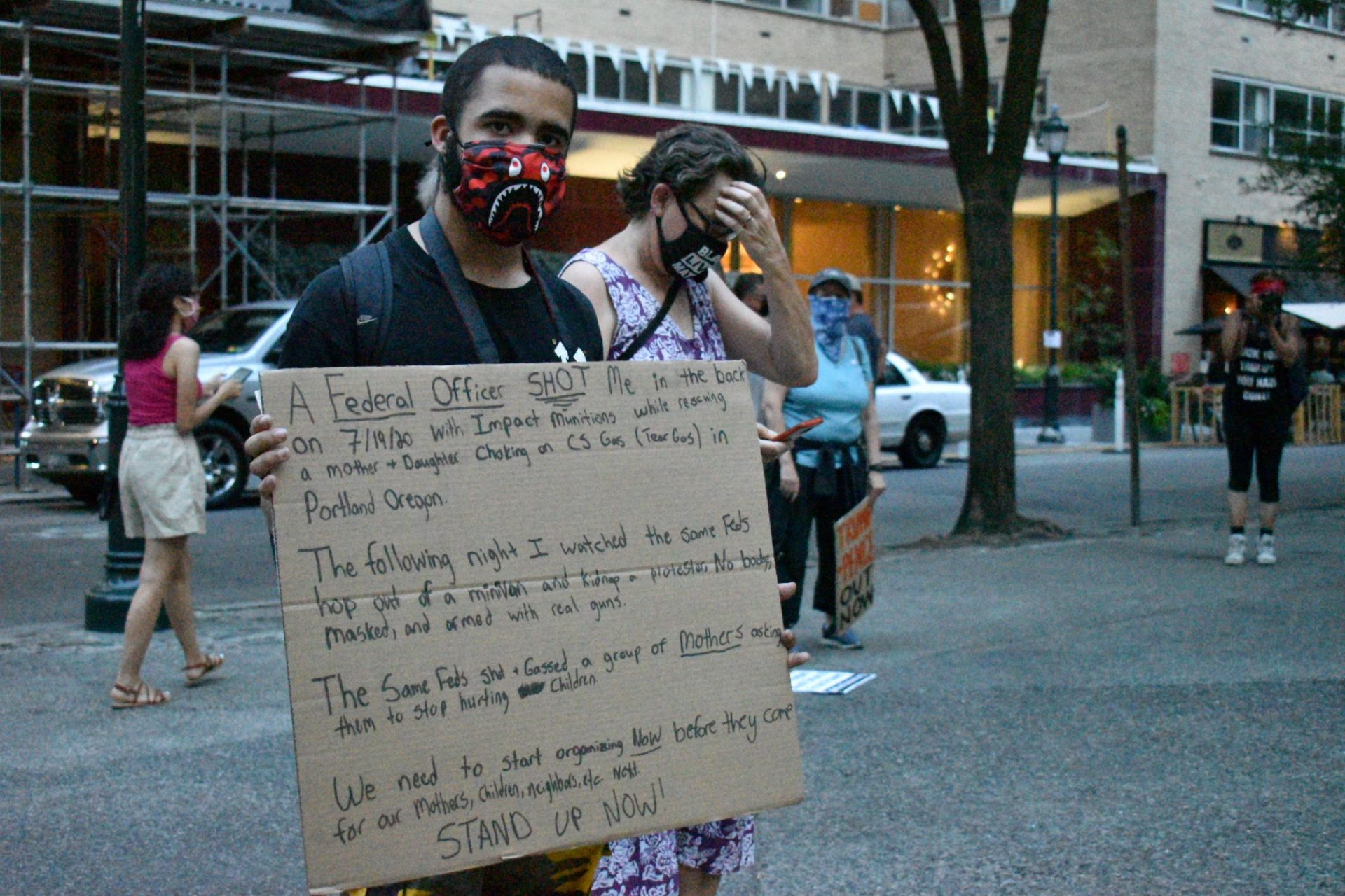 Jordan Johnson holds a sign detailing a recent incident with what he says were federal police in Portland, Oregon.