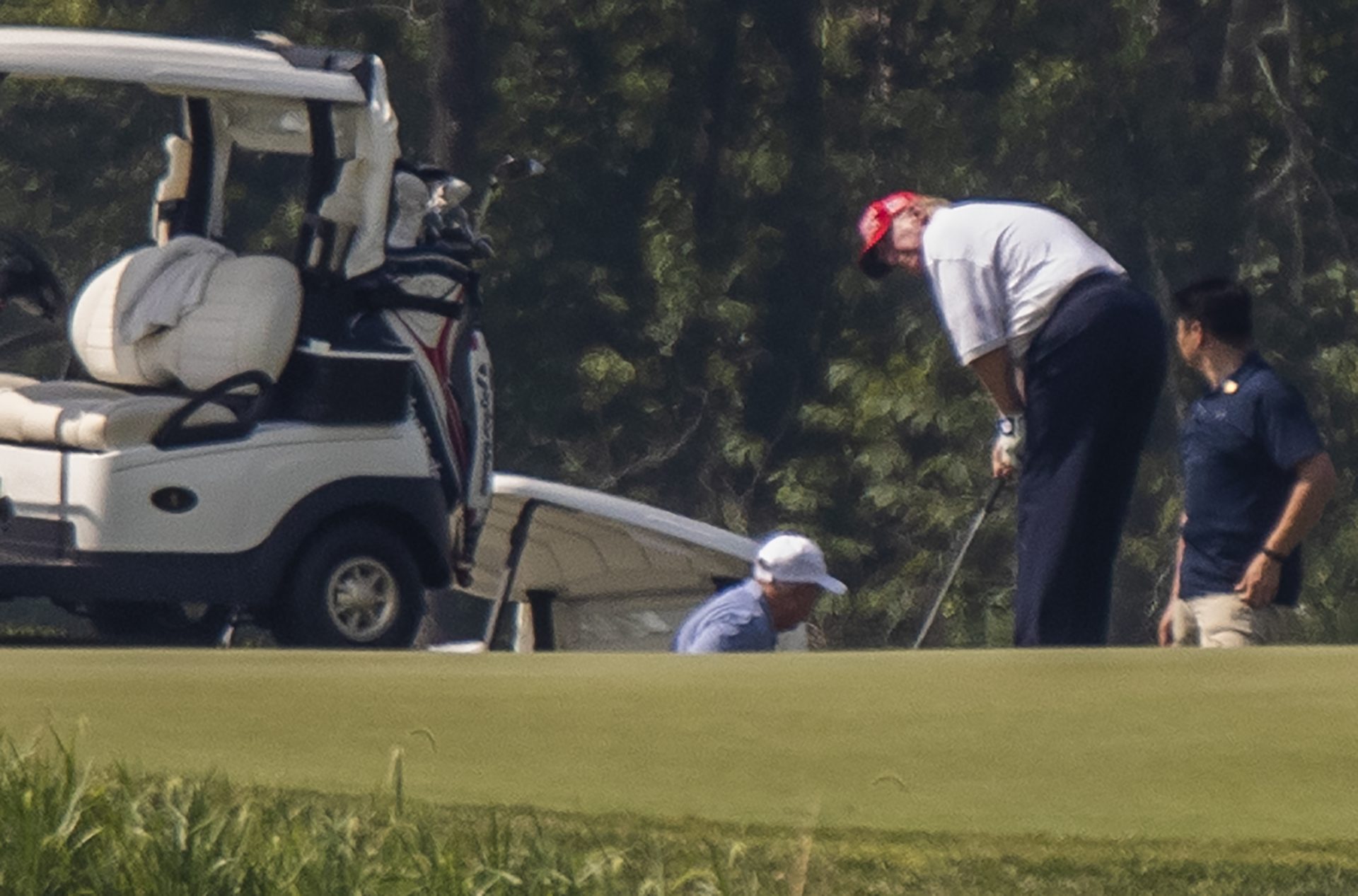 President Donald Trump and Sen. Lindsey Graham, R-S.C., back light blue shirt, play golf at Trump National Golf Club in Sterling, Va., as seen from the other side of the Potomac River in Darnestown, Md., Sunday, July 19, 2020.