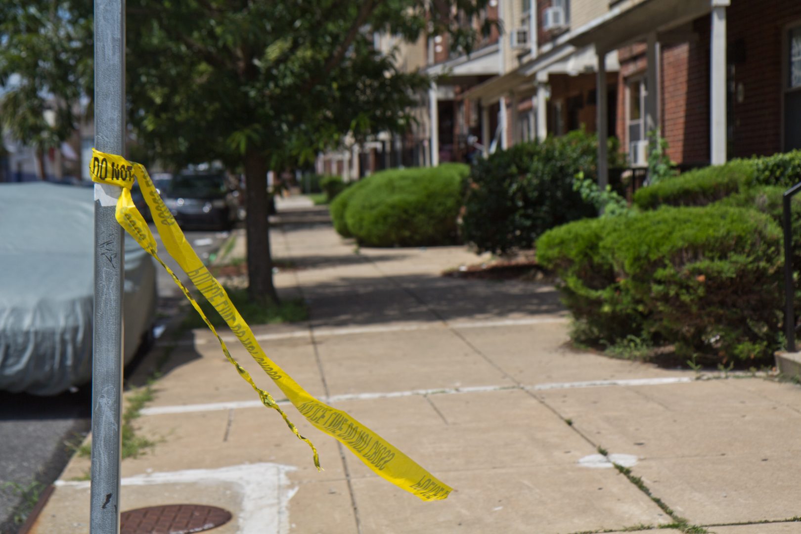 Remnants of crime scene tape on Brown Street in North Philadelphia where 5 were wounded in a shooting at a block party Saturday night. (Kimberly Paynter/WHYY)