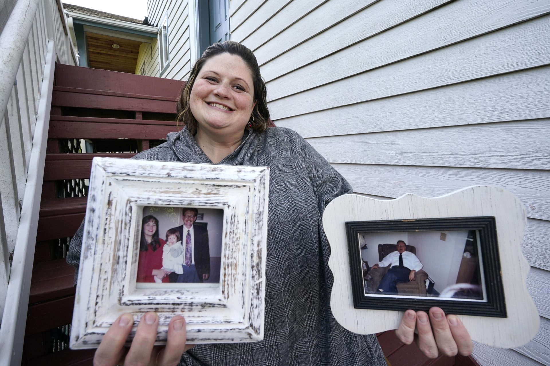 Caitlin Joyce holds family portraits, including her as a child with her parents and a photo of her 90-year-old grandfather, as she poses for a photo at her home Saturday, Aug. 29, 2020, in Edmonds, Wash. Joyce's family is forging ahead with a Thanksgiving holiday feast in Virginia and she plans to join them. They plan to set up plywood tables on sawhorses in a large garage so they can sit six feet apart where "It will be almost like camping."