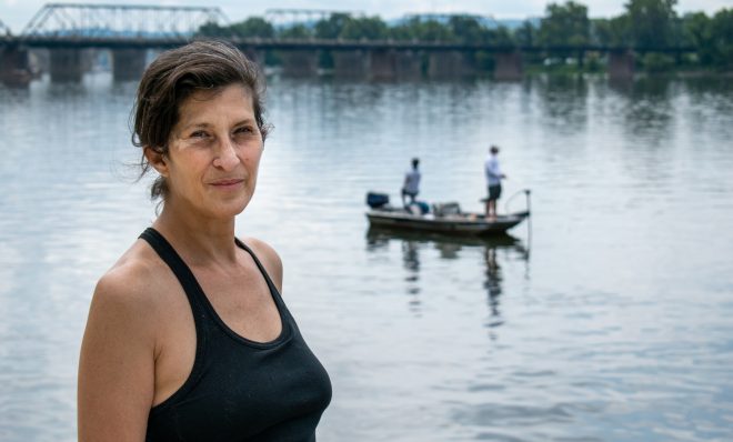 Ilyse Kazar stands along the Susquehanna river in Harrisburg next to a stormwater outflow while anglers fish nearby. Kazar, of Harrisburg, is one of the volunteers who collected water samples as part of the Lower Susquehanna Riverkeeper's annual water monitoring. 