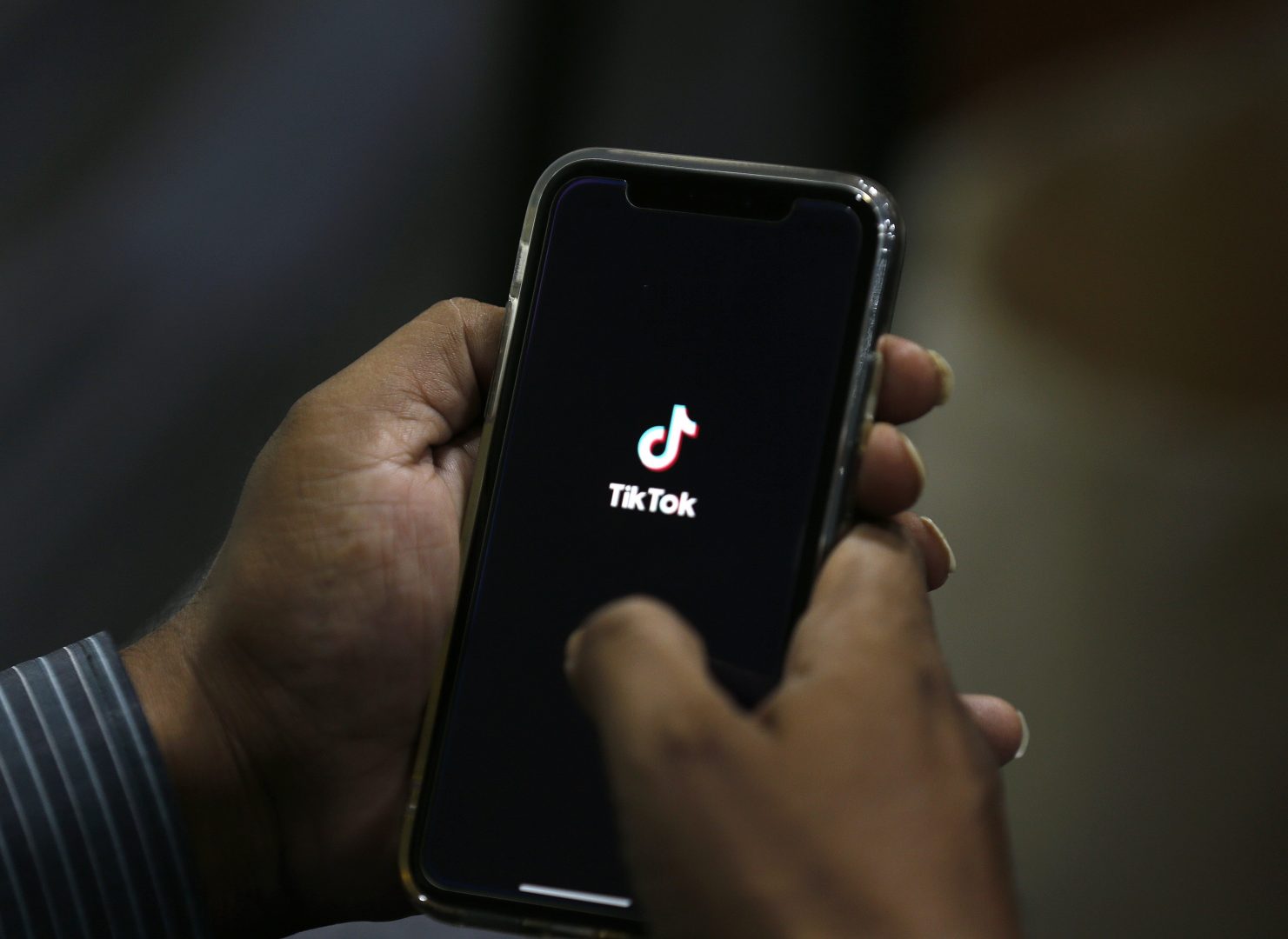 A man opens social media app 'TikTok' on his cell phone, in Islamabad, Pakistan, Tuesday, July 21, 2020. Pakistan has threatened the China-linked TikTok video service and blocked the Singapore-based Bigo Live streaming platform, citing what the regulating authority called widespread complaints about 