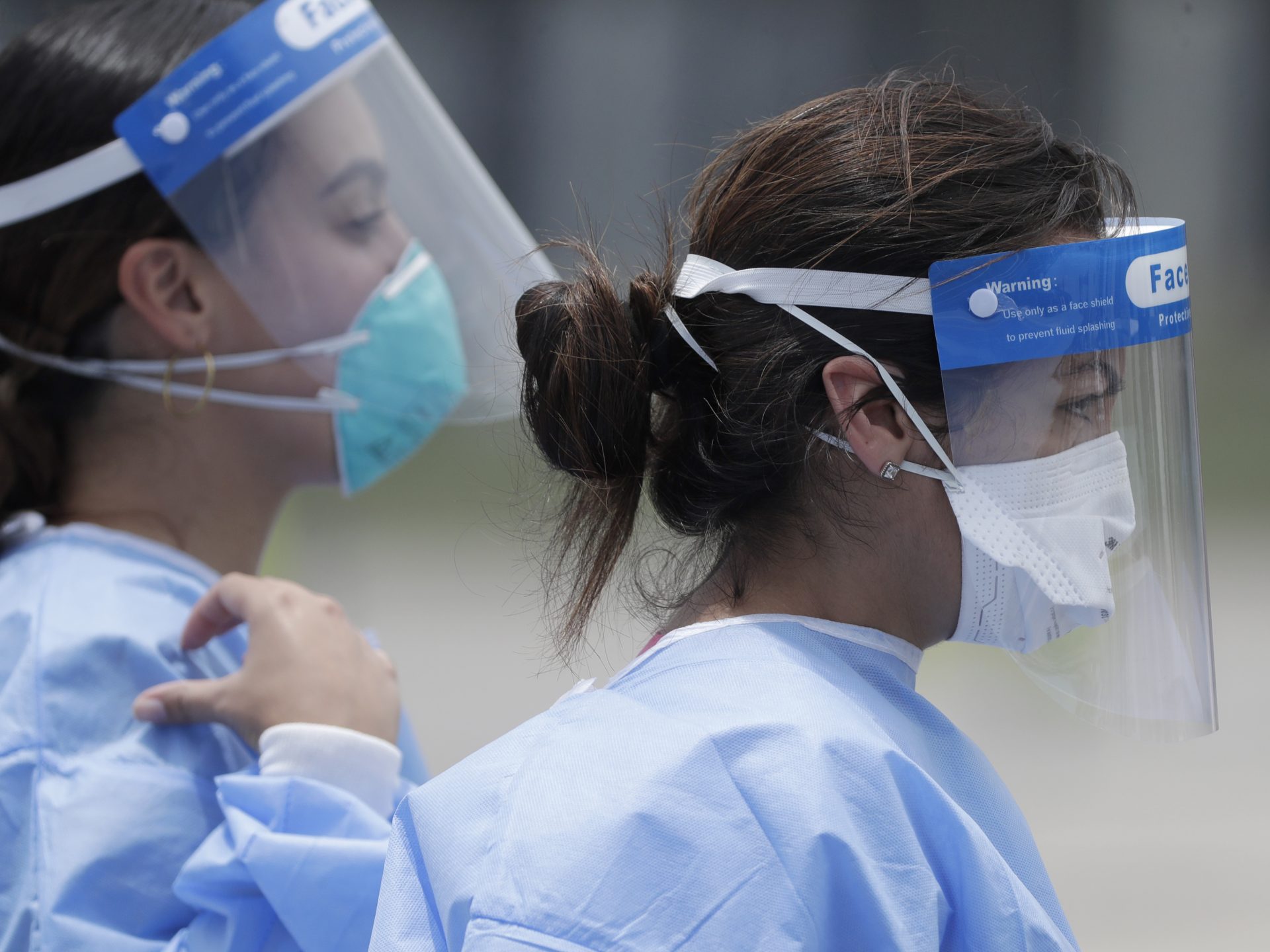 Healthcare workers walk to a tent, Wednesday, Aug. 5, 2020, at a COVID-19 testing site outside Hard Rock Stadium in Miami Gardens, Fla. State officials say Florida has surpassed 500,000 coronavirus cases. Meanwhile, testing is ramping up following a temporary shutdown of some sites because of Tropical Storm Isaias.