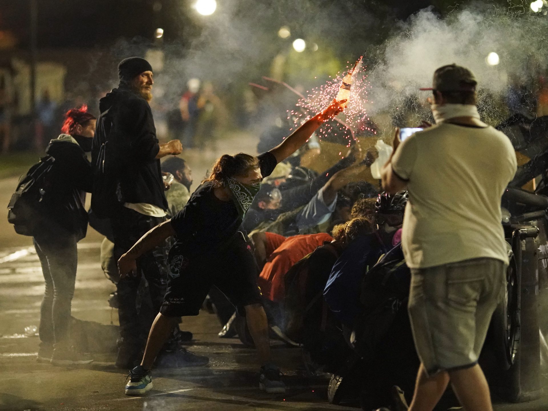A protester tosses an object toward police during clashes outside the Kenosha County Courthouse late Tuesday, Aug. 25, 2020, in Kenosha, Wis., on third night of unrest following the shooting of a Black man, Jacob Blake, whose attorney said he was paralyzed after being shot multiple times by police.