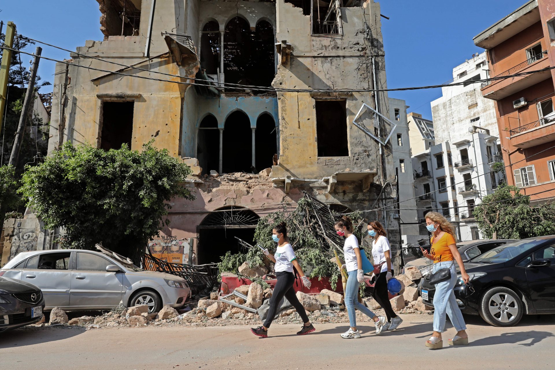 Women walk past a damaged building in the aftermath of Tuesday's blast that tore through Lebanon's capital on Wednesday. Rescuers searched for survivors in Beirut after a explosion killed more than 100 people and wounded thousands.