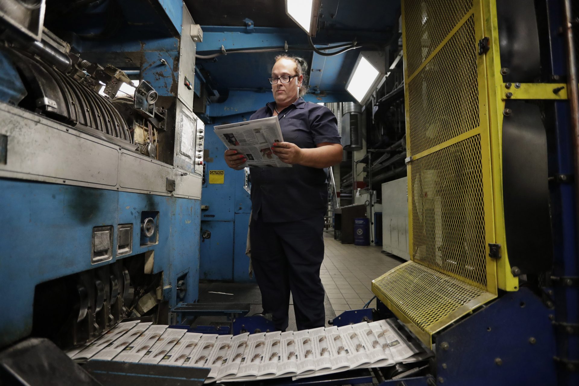 In this Tuesday, Aug. 6, 2019, photo, press operator Robin Yeager looks over the registration of a newspaper in Youngstown, Ohio. The Youngstown paper announced in June it would cease publication Saturday, Aug. 31, because of financial struggles, but the paper will be printed by the Tribune Chronicle, which has bought The Vindicator name, subscriber list and website from owners of the Youngstown publication.