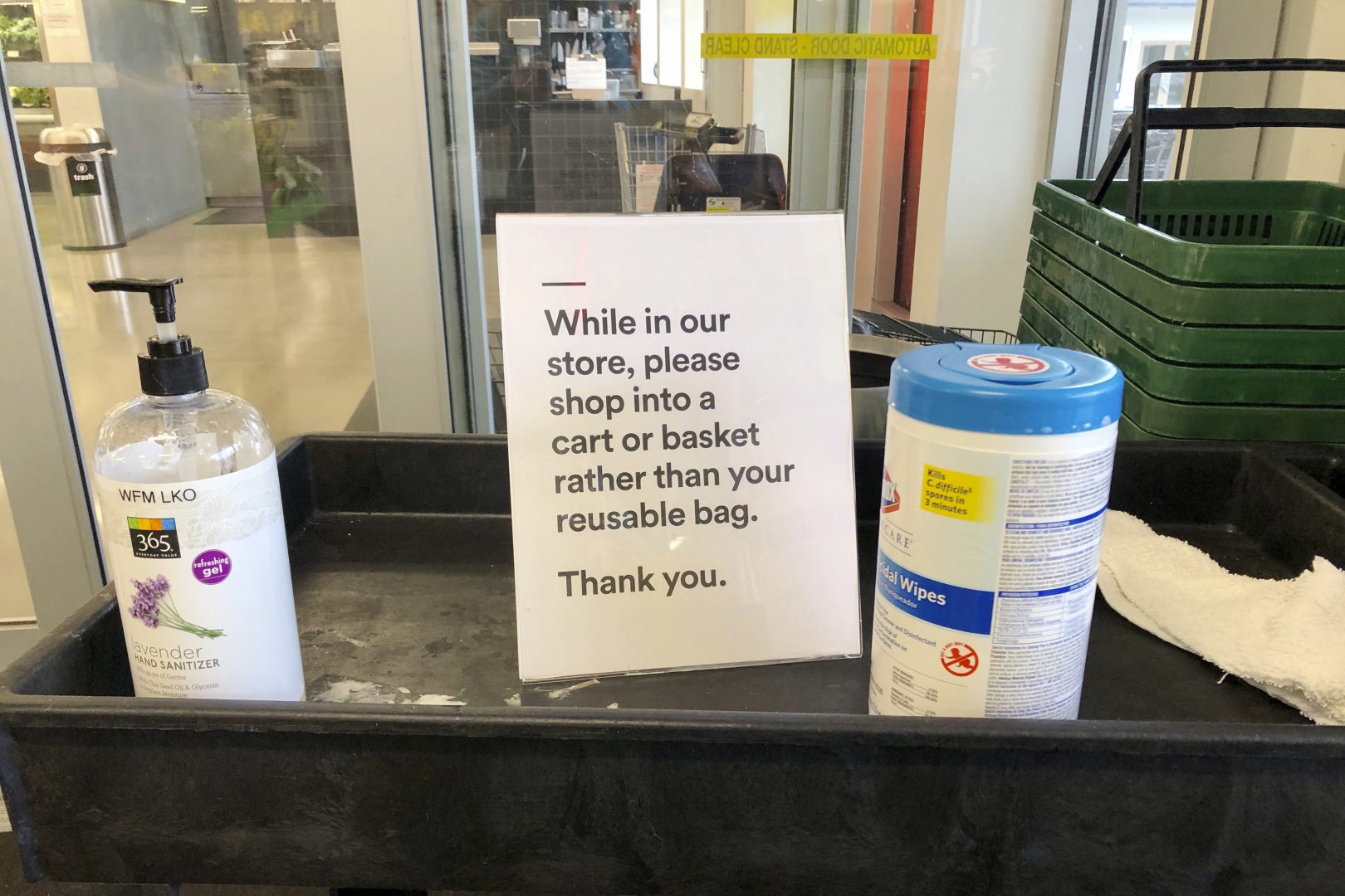 In this Sunday, March 29, 2020, photo, a sign posted at an entrance to a 365 Whole Foods store advises customers not to use their own bags while shopping in Lake Oswego, Ore. Just weeks earlier, cities and even states across the U.S. were busy banning straws, limiting takeout containers and mandating that shoppers bring reusable bags or pay a small fee. Grocery clerks became nervous that the virus could linger on reusable fabric bags, and their unions backed them up with demands to end plastic bag fees and suspend bag bans. The plastics industry seized the moment, lobbying to overturn existing bans on single-use plastics.  