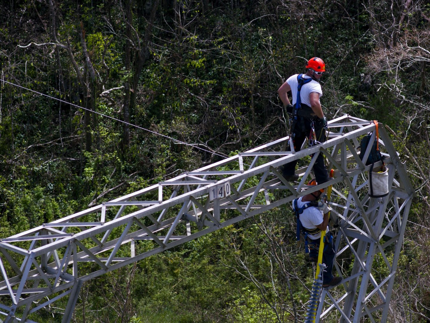 FILE - In this Sunday, Oct. 15, 2017, file photo, Whitefish Energy Holdings workers restore power lines damaged by Hurricane Maria in Barceloneta, Puerto Rico. A year after losing a $300 million no-bid contract to restore Puerto Rico's hurricane-shattered electric grid, Whitefish Energy Holdings has quietly been seeking and winning U.S. government contracts. (AP Photo/Ramon Espinosa, File)