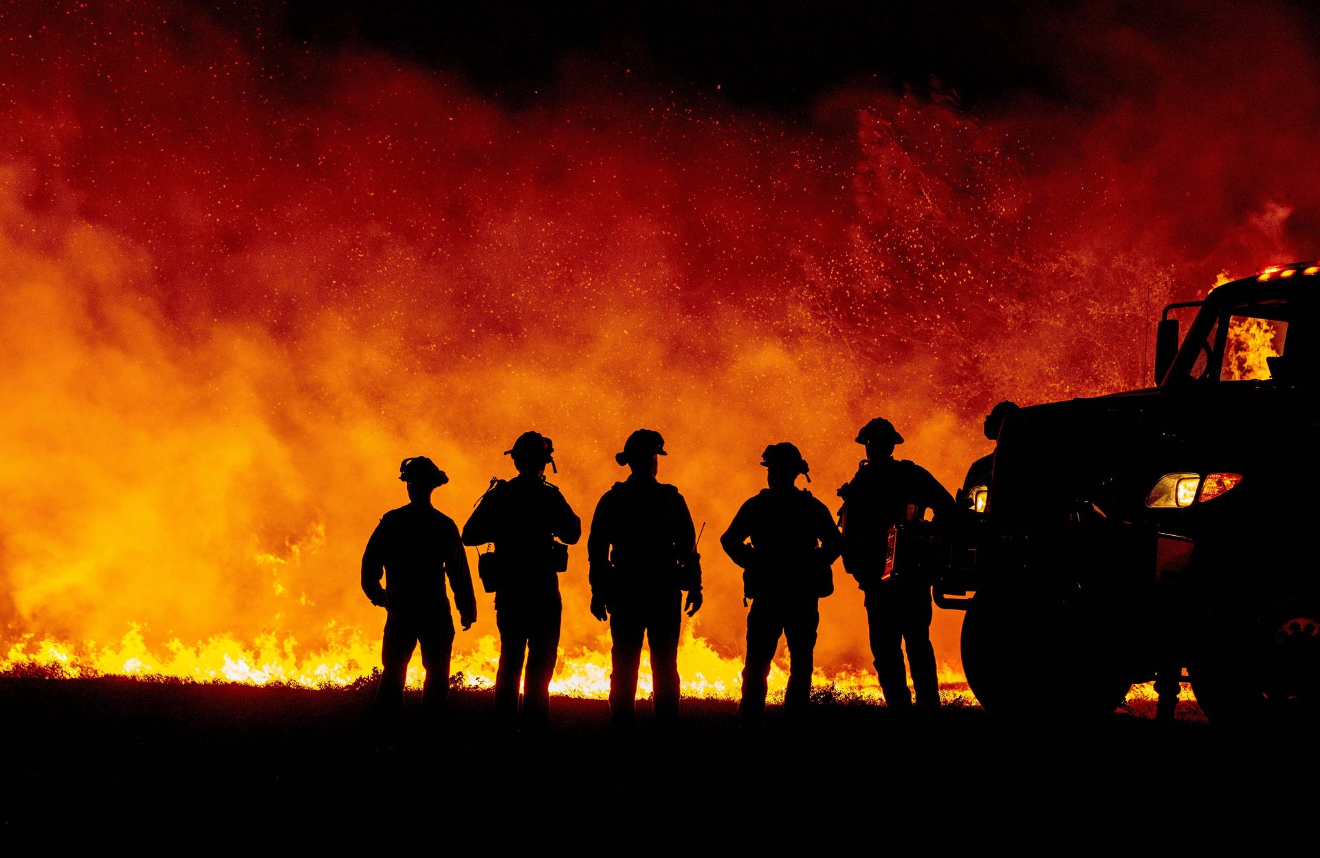 Butte County firefighters watch as flames quickly spread across a road at the Bear Fire in Oroville, Calif., on Wednesday. The local sheriff says three people died as a result of fires in the area.