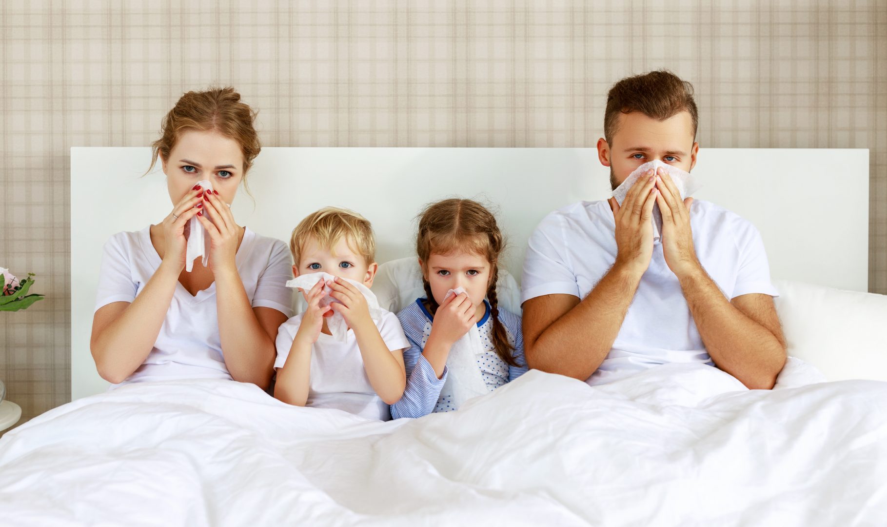 colds and viral diseases. family with runny nose and fever in bed at home