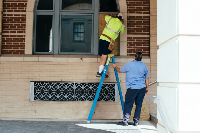 Construction workers repair broken windows at the Lancaster City Police Bureau building following a night of protests on September 14, 2020.