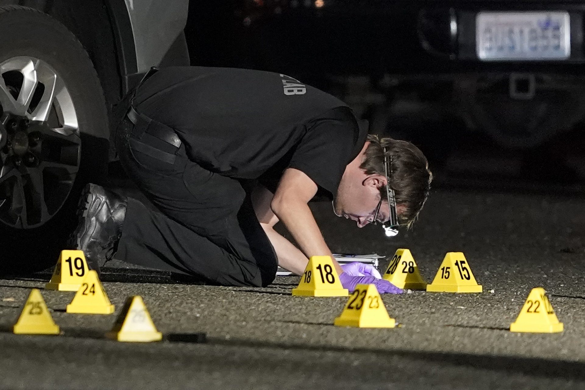 A Washington State Patrol Crime Lab worker looks at evidence markers in the early morning hours of Friday, Sept. 4, 2020, in Lacey, Wash. at the scene where Michael Reinoehl was killed Thursday night as investigators moved in to arrest him. Reinoehl had been suspected of fatally shooting a supporter of a right-wing group in Portland, Oregon, last week after a caravan of Donald Trump backers rode through downtown Portland.