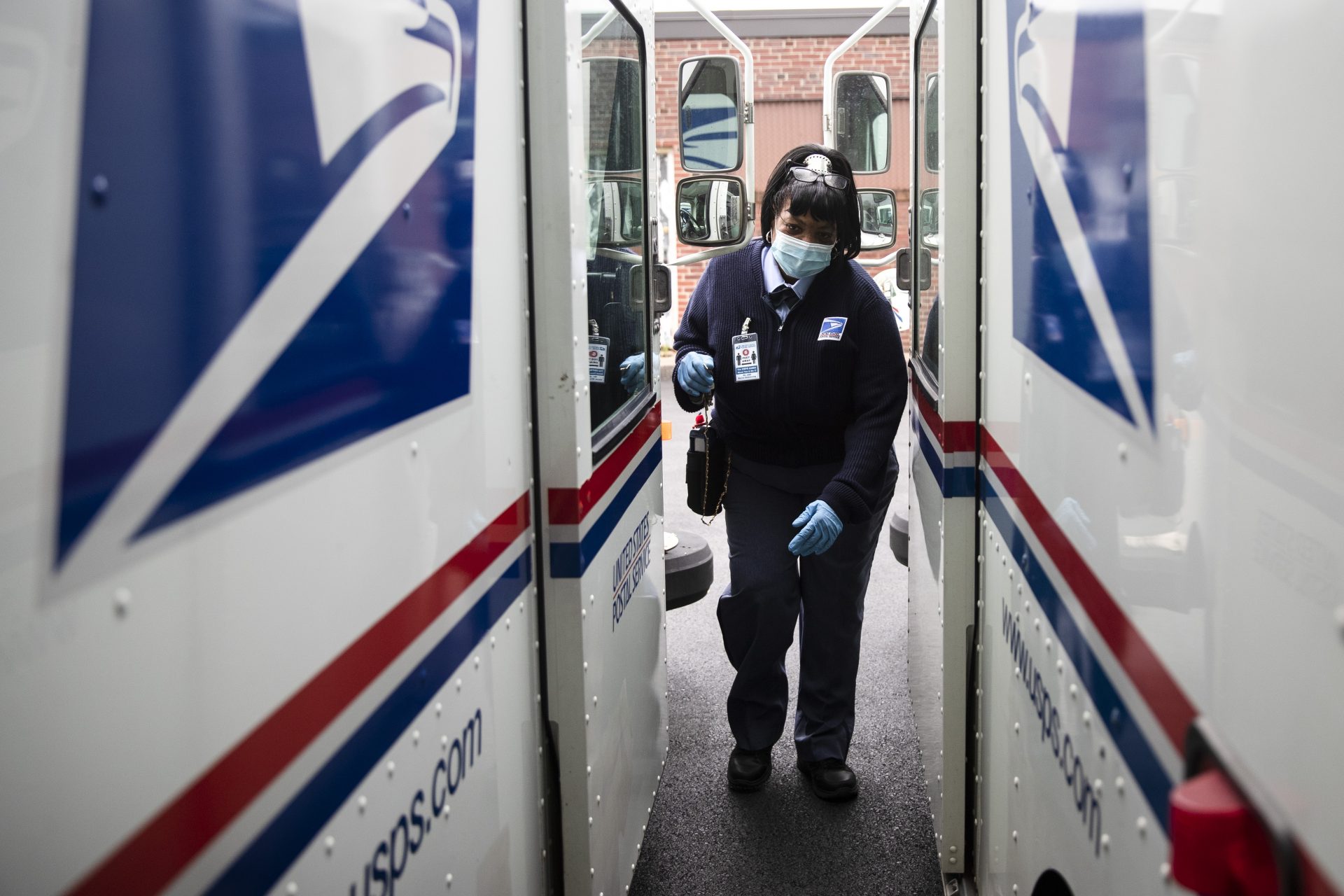 In this May 6, 2020, photo, United States Postal Service carrier Henrietta Dixon gets into her truck to deliver mail in Philadelphia. Officials from six states and the District of Columbia are in court Thursday, Sept. 24, to ask a federal judge to halt alleged slowdowns at the U.S. Postal Service that they say threaten the upcoming presidential election,