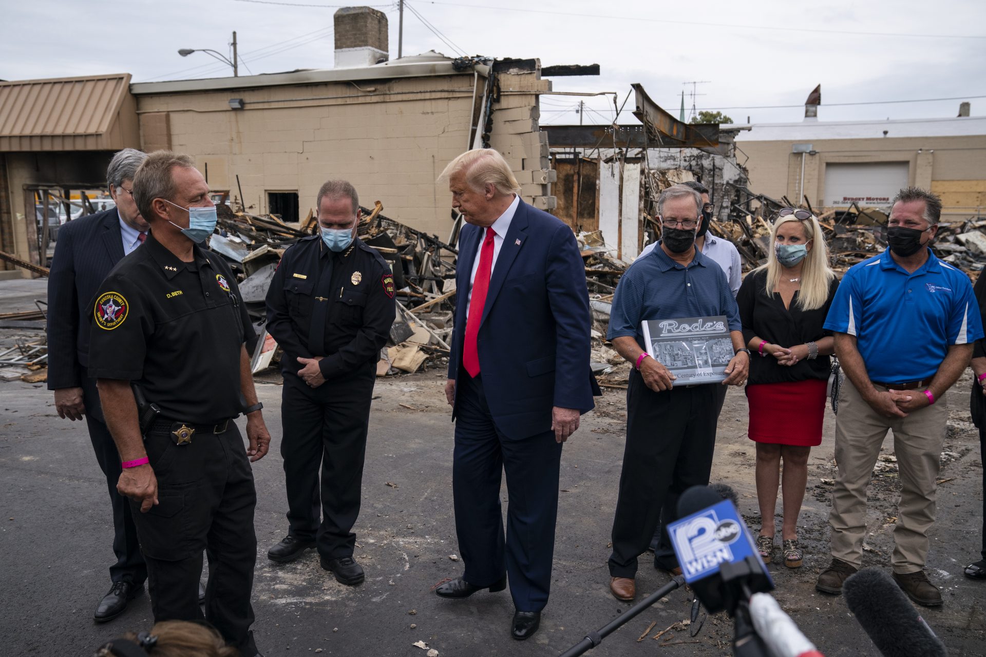 President Donald Trump speaks with business owners and law enforcement officials Tuesday, Sept. 1, 2020, as he tours an area damaged during demonstrations after a police officer shot Jacob Blake in Kenosha, Wis. At left is Kenosha County Sheriff David Beth.