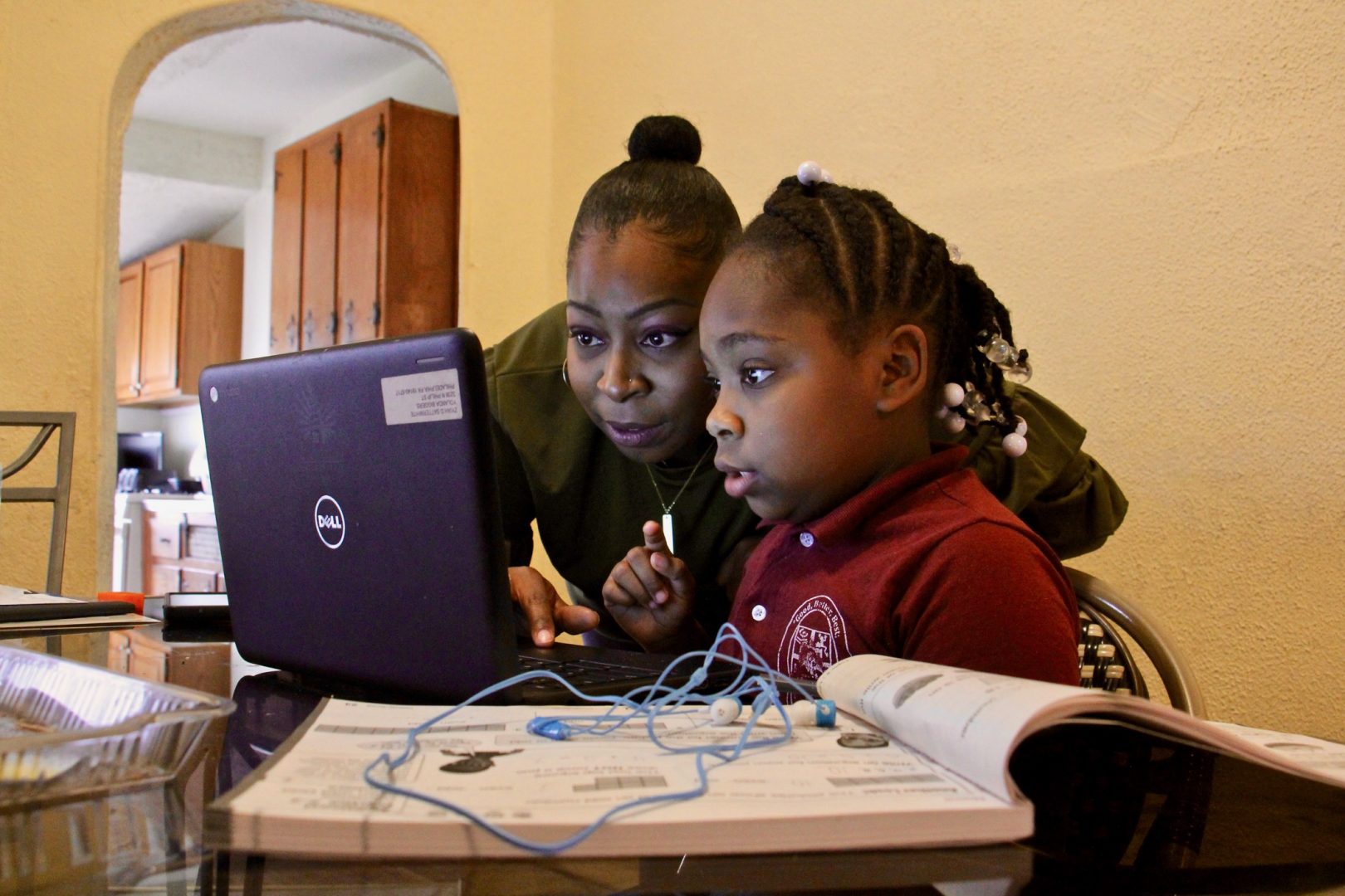 Yolanda Biggers helps her daughter, Zyiah Satterwhite, 7, find her assignment. Zyiah attends second grade virtually from her home in Fairhill.