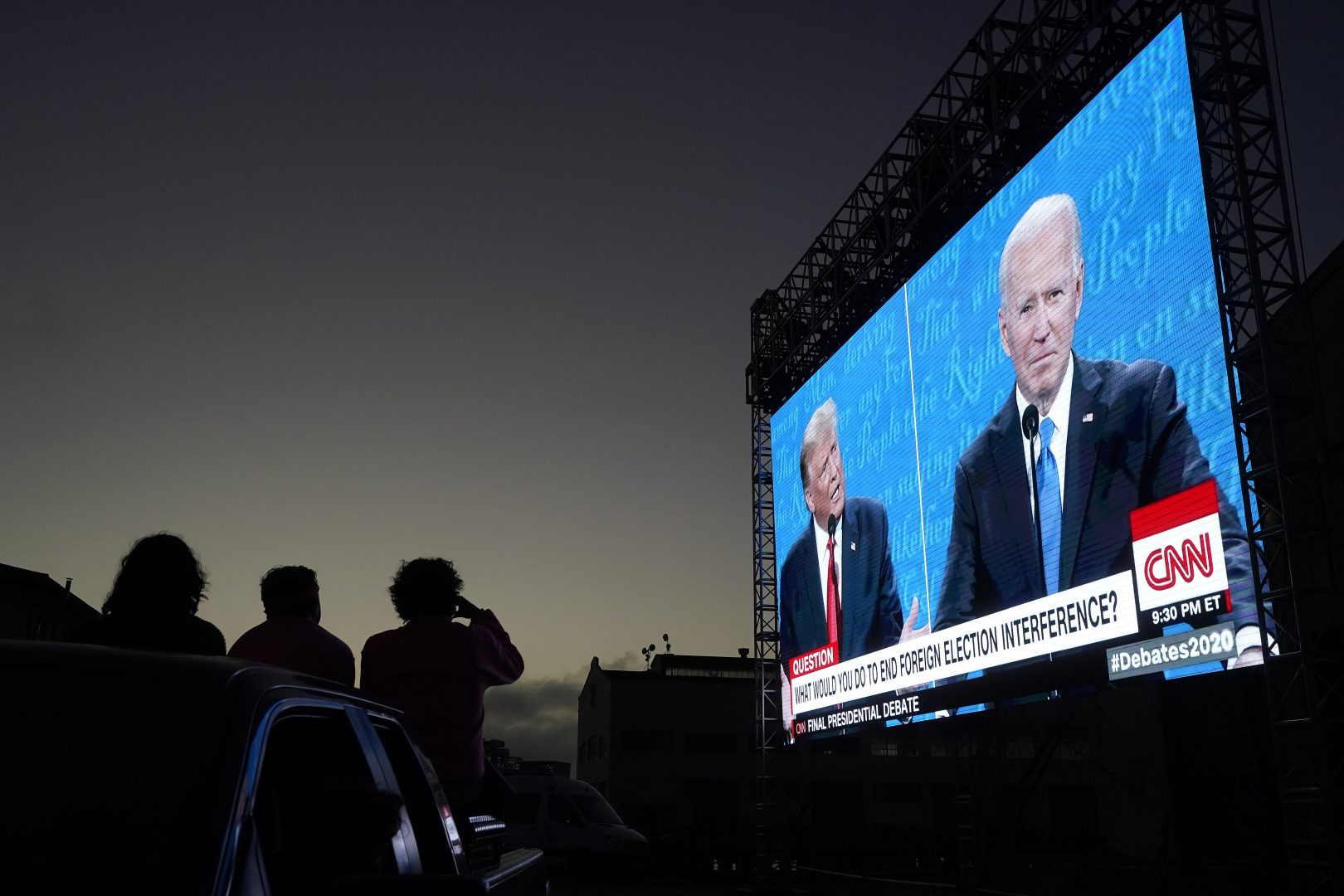 People watch from their vehicle as President Donald Trump, on left of video screen, and Democratic presidential candidate former Vice President Joe Biden speak during a Presidential Debate Watch Party at Fort Mason Center in San Francisco, Thursday, Oct. 22, 2020. The debate party was organized by Manny's, a San Francisco community meeting and learning place.