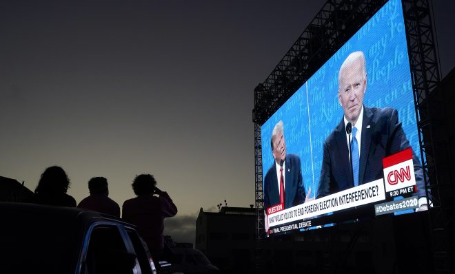 People watch from their vehicle as President Donald Trump, on left of video screen, and Democratic presidential candidate former Vice President Joe Biden speak during a Presidential Debate Watch Party at Fort Mason Center in San Francisco, Thursday, Oct. 22, 2020. The debate party was organized by Manny's, a San Francisco community meeting and learning place.