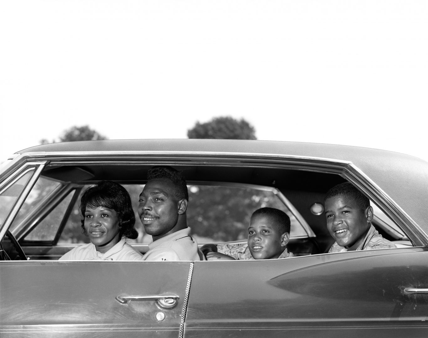 1960s SIDE VIEW OUTDOOR SMILING AFRICAN AMERICAN FAMILY FATHER MOTHER TWO SONS SITTING IN FOUR DOOR SEDAN AUTOMOBILE  (Photo by H. Armstrong Roberts/ClassicStock/Getty Images)