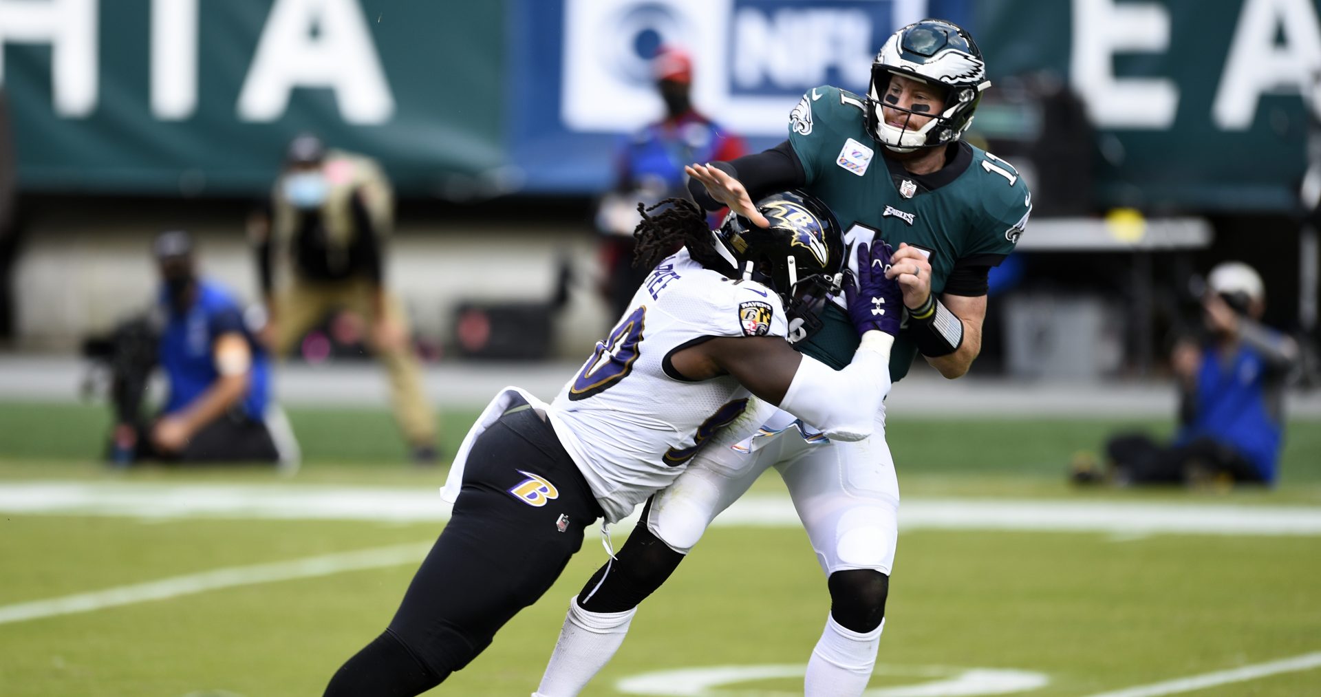 Philadelphia Eagles' Carson Wentz (11) is hit by Baltimore Ravens' Pernell McPhee (90) during the second half of an NFL football game, Sunday, Oct. 18, 2020, in Philadelphia.