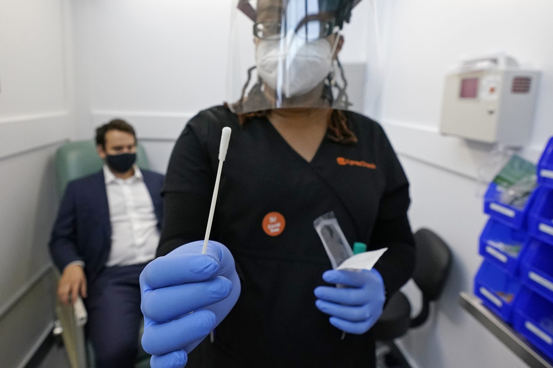 Medical assistant Aneka Gopaulsingh holds a swab after testing Julian Bernstein at the new XpresCheck COVID-19 testing facility at Boston Logan International Airport, Wednesday, Oct. 28, 2020, in Boston. The testing site is open for airport and airline employees, and will open to passengers and the general public in mid-November.