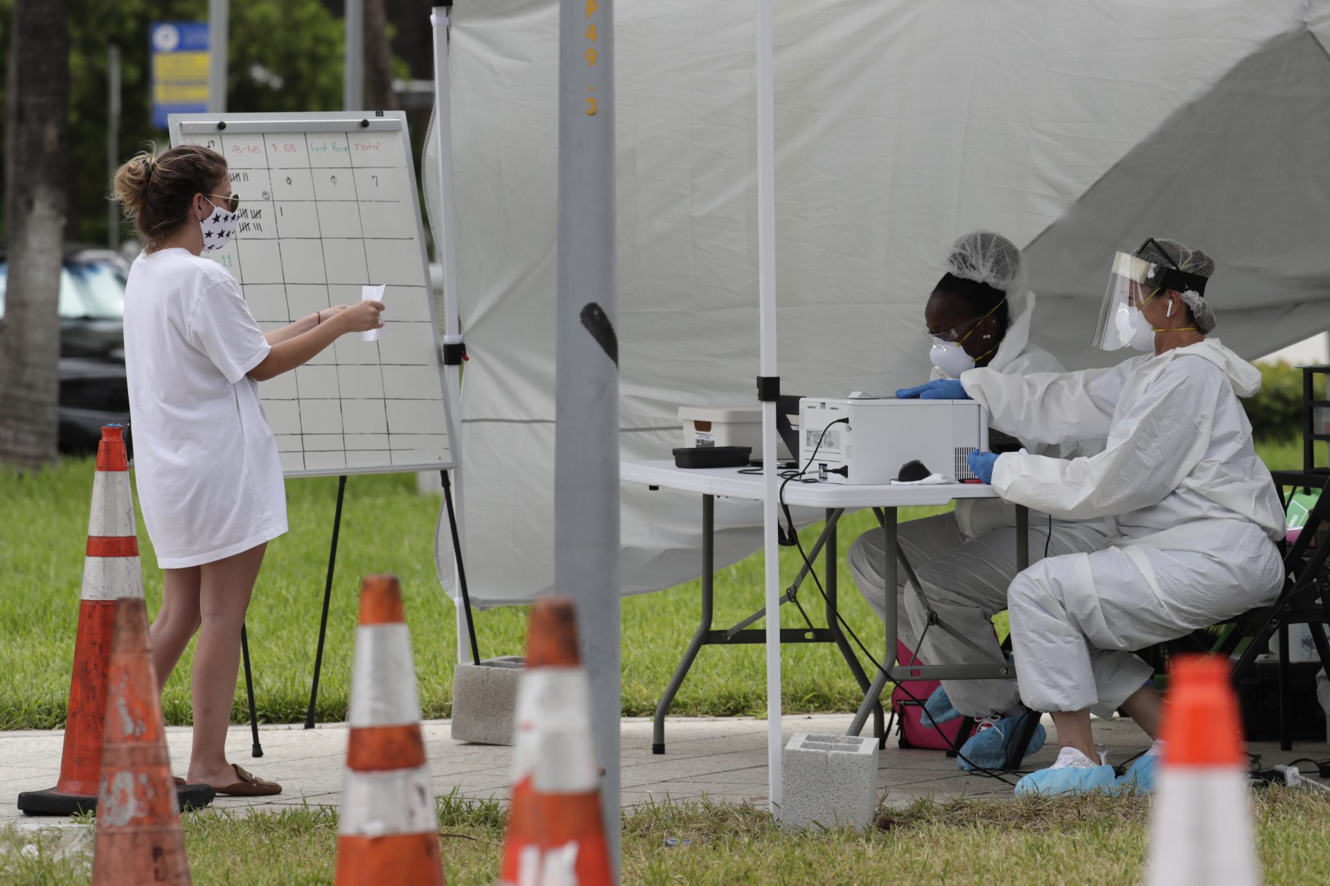 In this Friday, July 17, 2020 file photo, health care workers take information from people in line at a walk-up COVID-19 testing site during the coronavirus pandemic in Miami Beach, Fla. After months of struggling to ramp up coronavirus testing, the U.S. is now capable of testing some 3 million people daily thanks to a growing supply of rapid tests. But the testing boom comes with a new challenge: keeping track of the results.