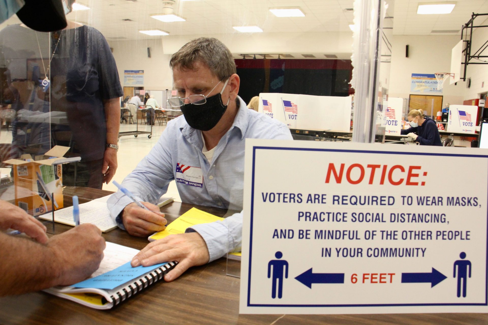 Poll worker Chuck Kellander interacts with voters through a plexiglass screen at Belmont Hill Elementary School in Bensalem, Bucks County. 