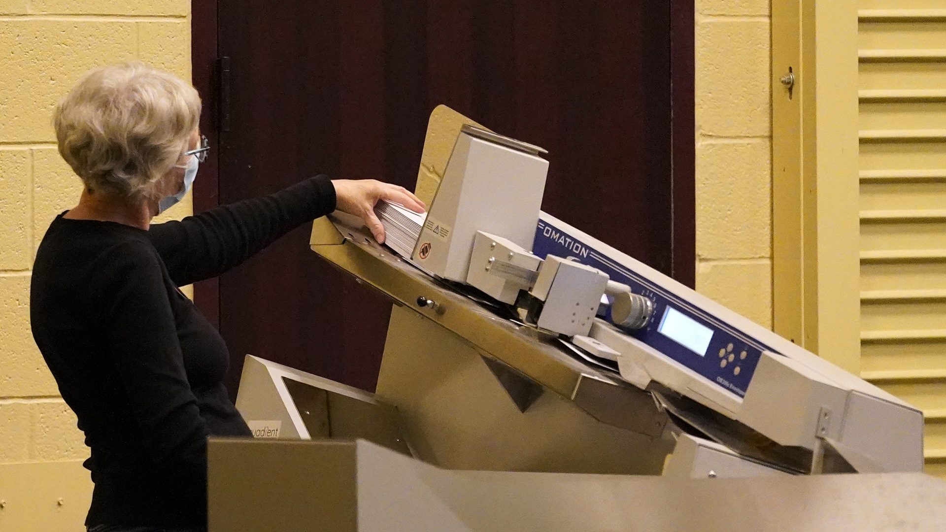 A worker scans mail-in ballots through a counting machine before they are counted, Wednesday, Nov. 4, 2020, at the convention center in Lancaster, Pa., following Tuesday's election.