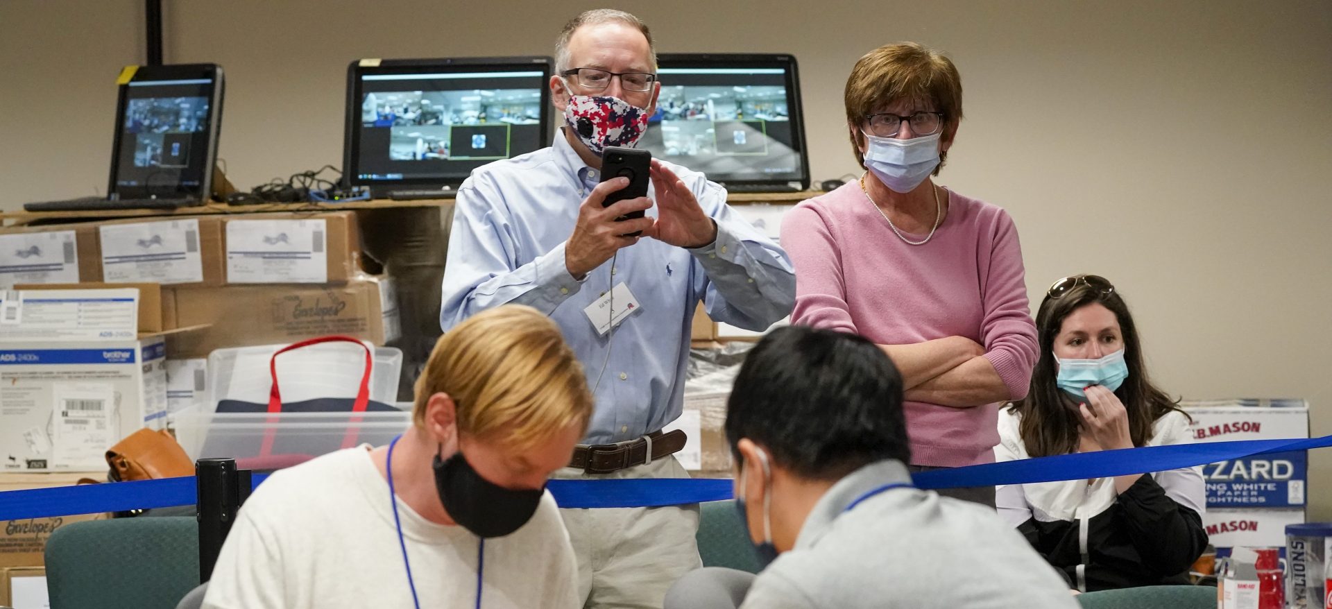 Republican canvas observer Ed White, center, and Democratic canvas observer Janne Kelhart, watch as Lehigh County workers count ballots as vote counting in the general election continues, Friday, Nov. 6, 2020, in Allentown, Pa.