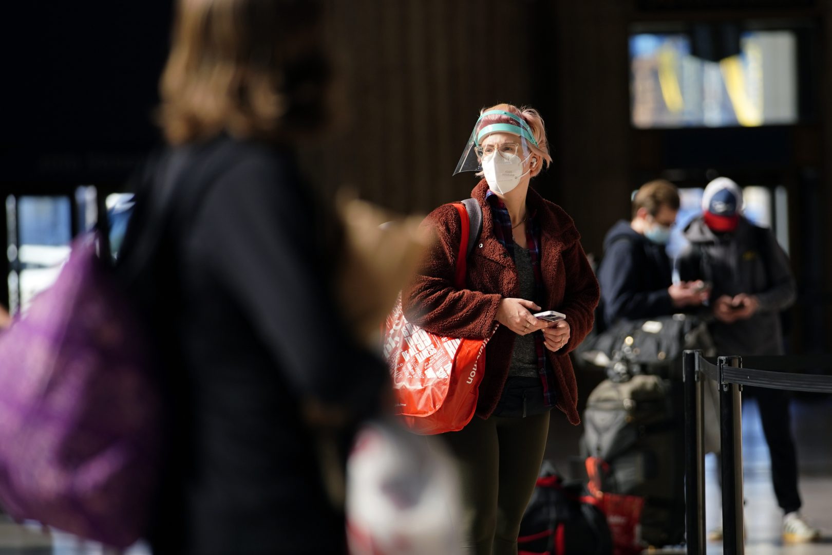 A woman waits in line for a train at the 30th Street Station ahead of the Thanksgiving holiday, Friday, Nov. 20, 2020, in Philadelphia. As governors and mayors grapple with an out-of-control pandemic, they are ratcheting up mask mandates and imposing restrictions on small indoor gatherings, which have been blamed for accelerating the spread of the coronavirus.