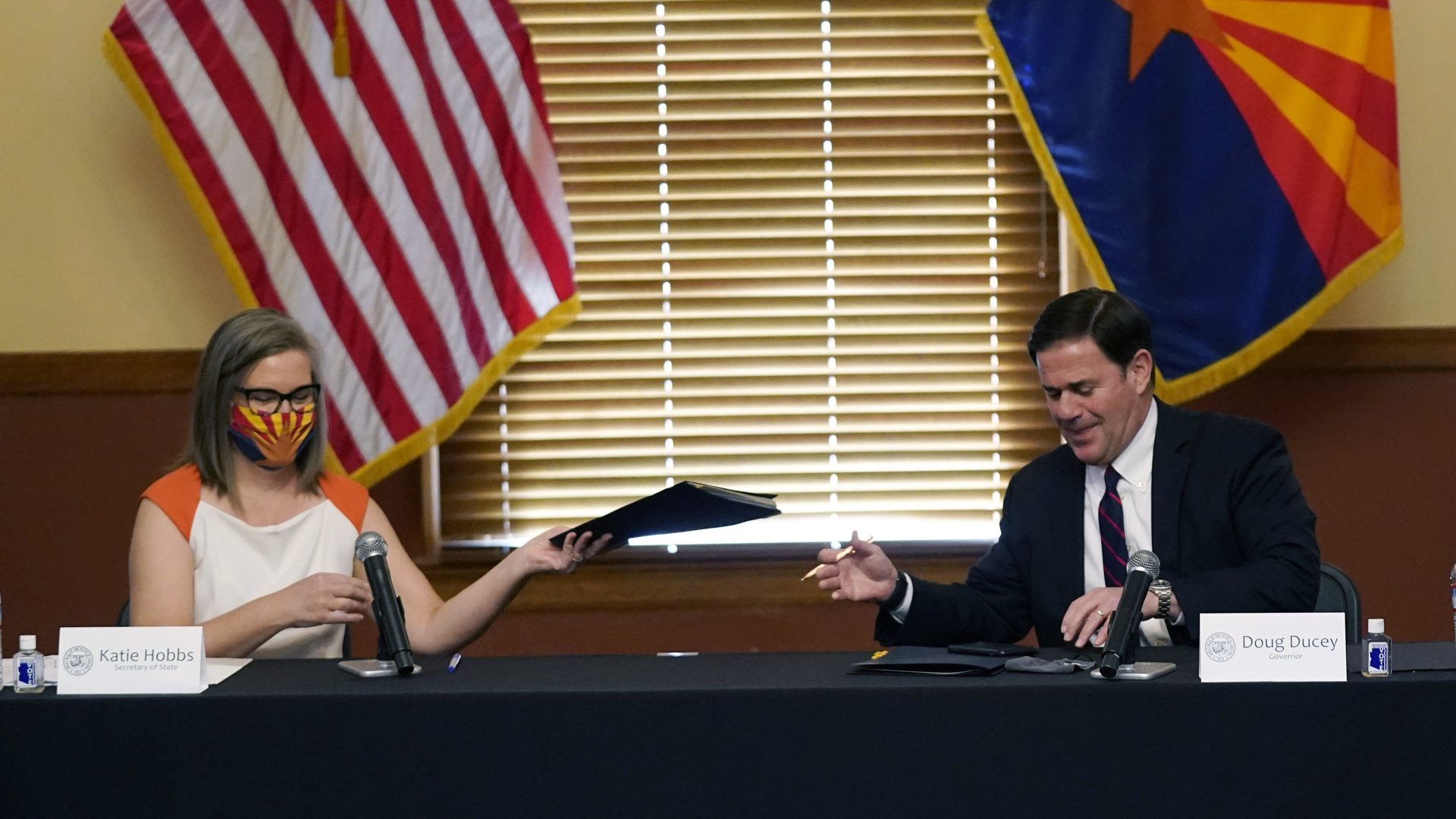 Arizona Secretary of State Katie Hobbs, left, and Arizona Gov. Doug Ducey exchange election documents to sign to certify the election results for federal, statewide, and legislative offices and statewide ballot measures at the official canvass at the Arizona Capitol Monday, Nov. 30, 2020, in Phoenix. (AP Photo/Ross D. Franklin, Pool)