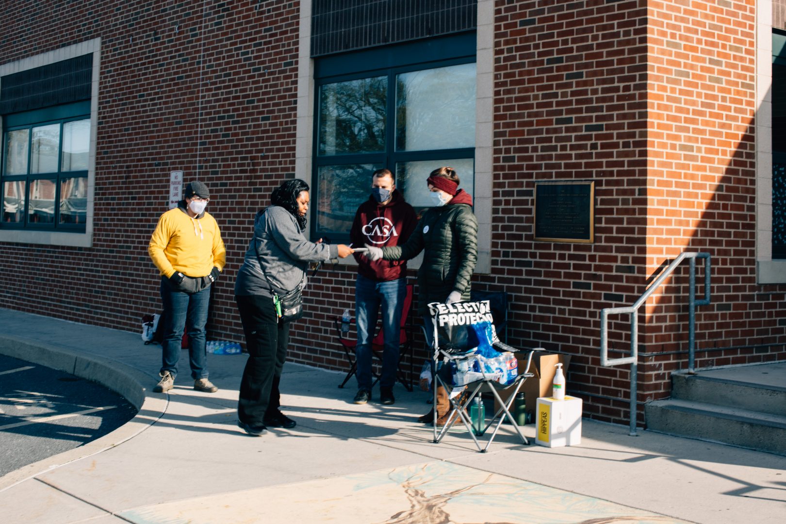 Voter Guardians with CASA hand a face mask to a woman at Harrisburg's 7th Ward 2nd Precinct on November 3, 2020.