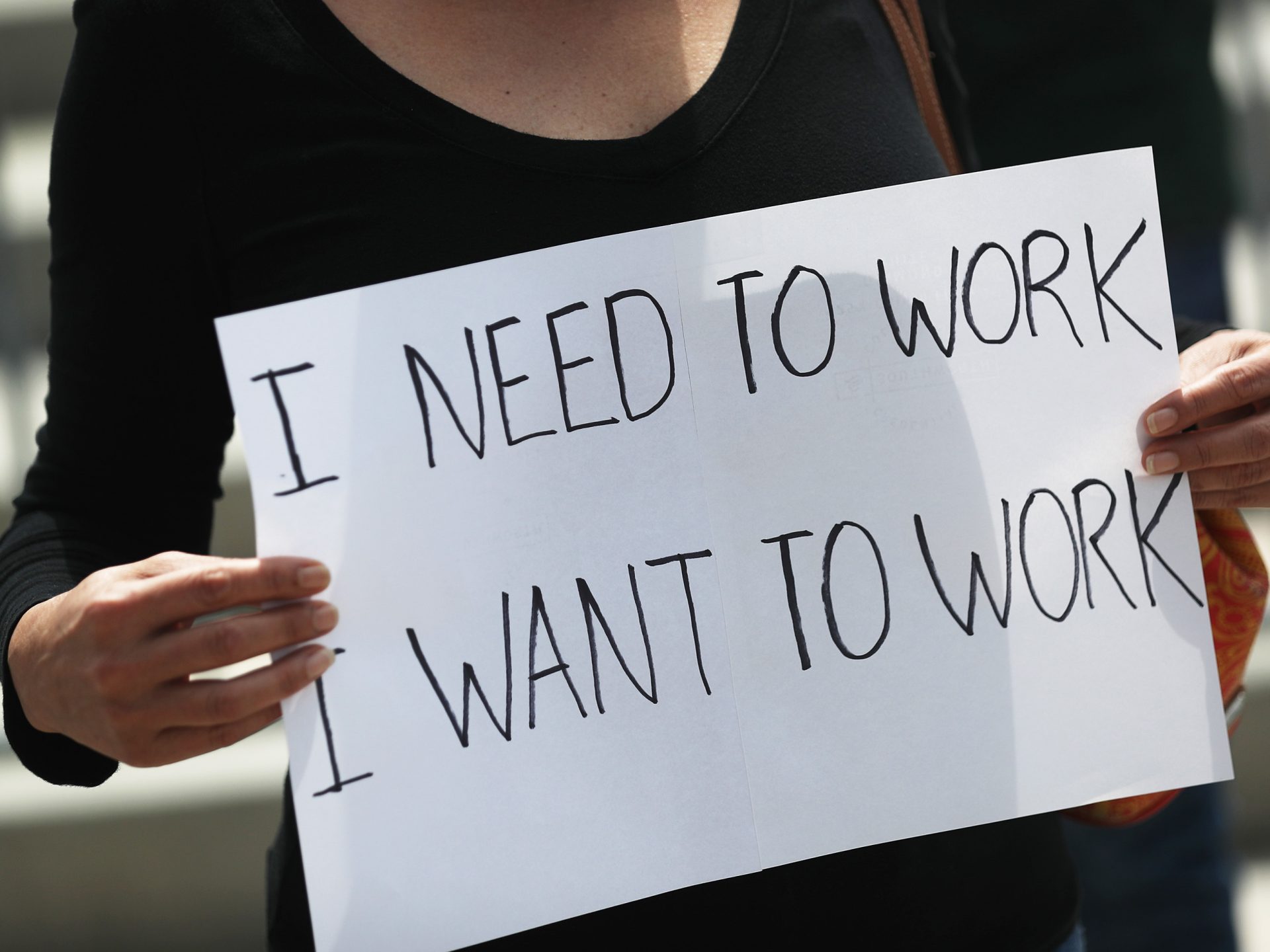 A protester holds a sign as she joins with restaurant owners, workers and supporters on July 10, 2020, to protest measures in Miami to close indoor seating amid a rise in coronavirus cases. The number of unemployment claims rose for a second week, reinforcing concerns about the economy.