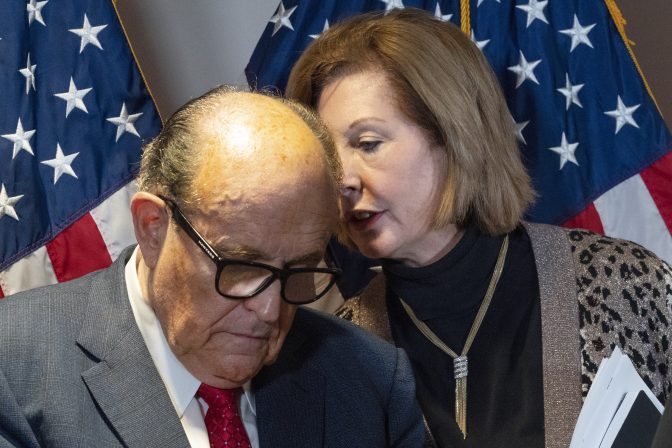 Former Mayor of New York Rudy Giuliani, left, listens to Sidney Powell, both lawyers for President Donald Trump, during a news conference at the Republican National Committee headquarters, Thursday Nov. 19, 2020, in Washington.