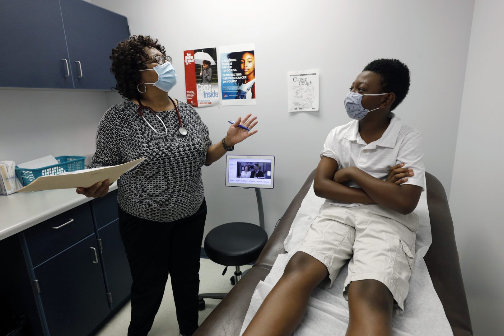 Jeremiah Young, 11, right, listens as Dr. Janice Bacon, a primary care physician, with Central Mississippi Health Services explains the necessity of receiving inoculations prior to attending school, Aug. 14, 2020, while at the Community Health Care Center on the Tougaloo College campus in Tougaloo, Miss. As a Black primary care physician, Bacon has created a safe space for her Black patients during the coronavirus pandemic.