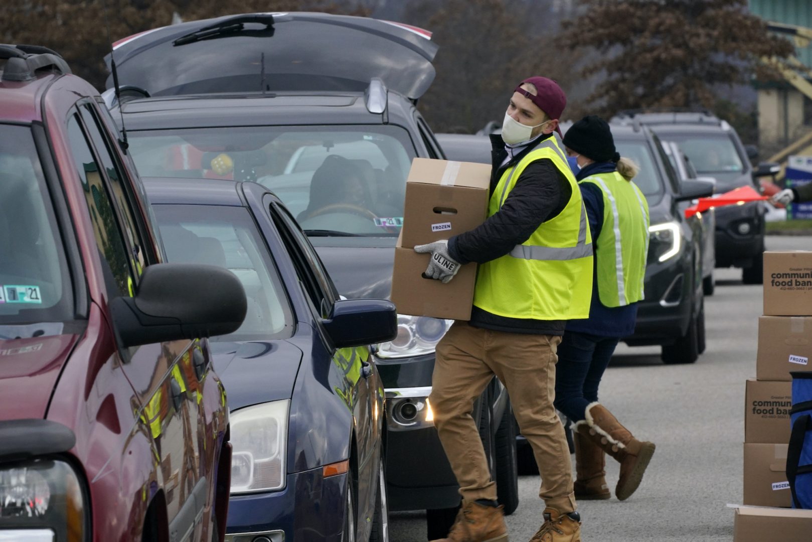 Volunteers load boxes of food into a car during a Greater Pittsburgh Community Food bank drive-up food distribution in Duquesne, Pa., Monday, Nov. 23, 2020.