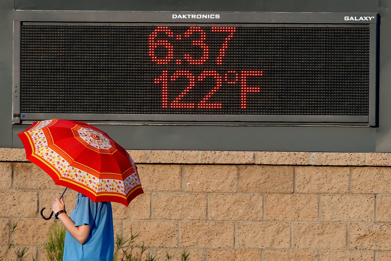 PHOENIX, AZ - JUNE 20:  A pedestrian uses an umbrella to get some relief from the sun as she walks past a sign displaying the temperature on June 20, 2017 in Phoenix, Arizona.  Record temperatures of 118 to 120 degrees were expected on Tuesday for the Phoenix-metro area. 