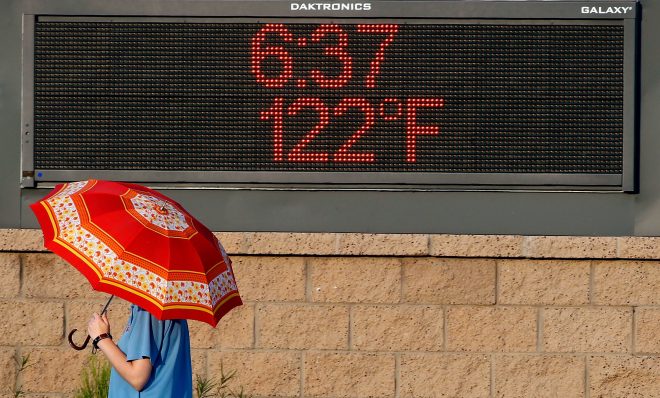PHOENIX, AZ - JUNE 20:  A pedestrian uses an umbrella to get some relief from the sun as she walks past a sign displaying the temperature on June 20, 2017 in Phoenix, Arizona.  Record temperatures of 118 to 120 degrees were expected on Tuesday for the Phoenix-metro area. 