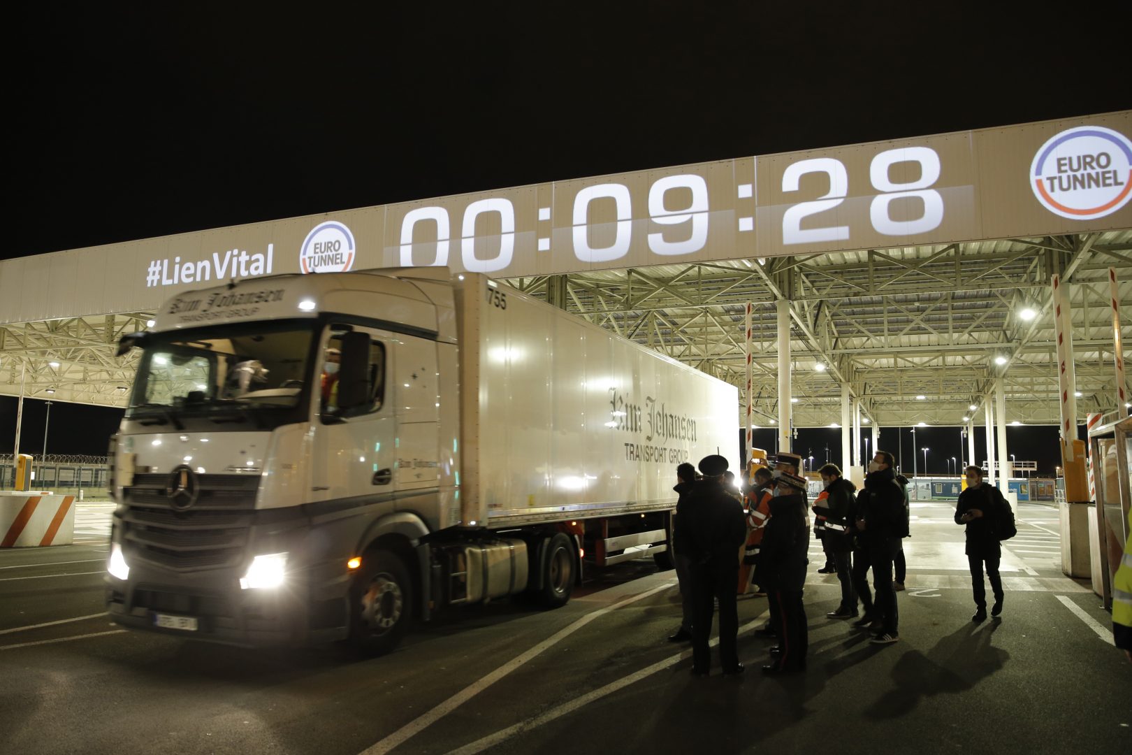 People watch the first truck, from Estonia, entering the Eurotunnel terminal Friday, Jan.1, 2021 in Coquelles, northern France. Eleven months after Britain's formal departure from the EU, Brexit becomes a fact of daily life on Friday, once a transition period ends and the U.K. fully leaves the world's most powerful trading bloc. (AP Photo/Lewis Joly, Pool)