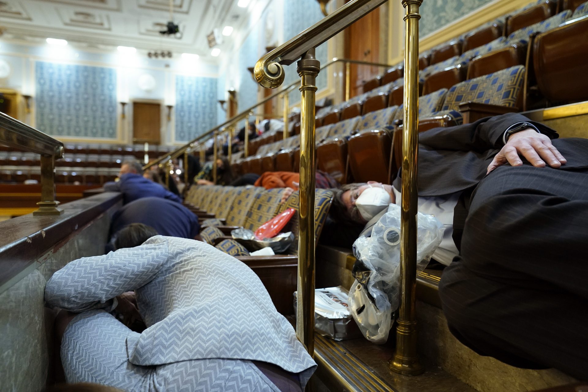 People shelter in the House gallery as protesters try to break into the House Chamber at the U.S. Capitol on Wednesday, Jan. 6, 2021, in Washington.