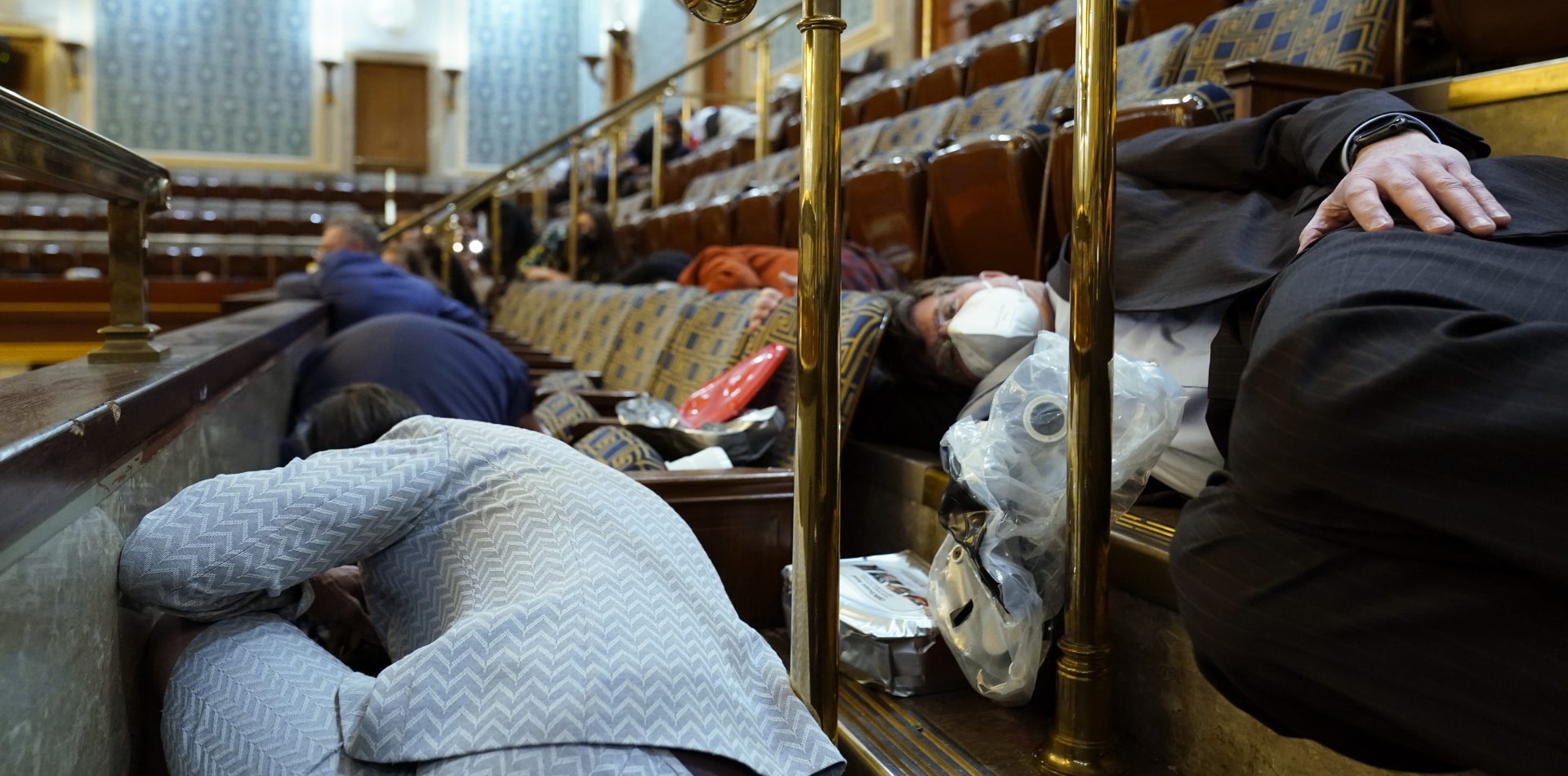 People shelter in the House gallery as protesters try to break into the House Chamber at the U.S. Capitol on Wednesday, Jan. 6, 2021, in Washington.