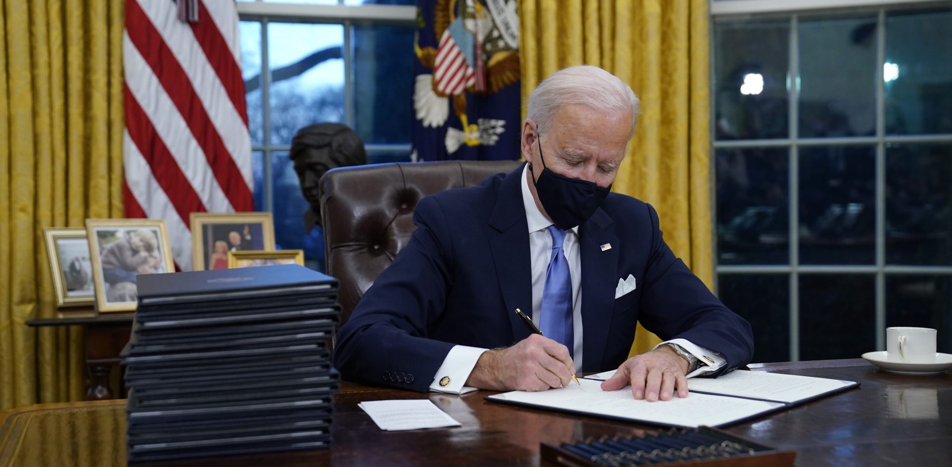 President Joe Biden signs his first executive order in the Oval Office of the White House on Wednesday, Jan. 20, 2021, in Washington.