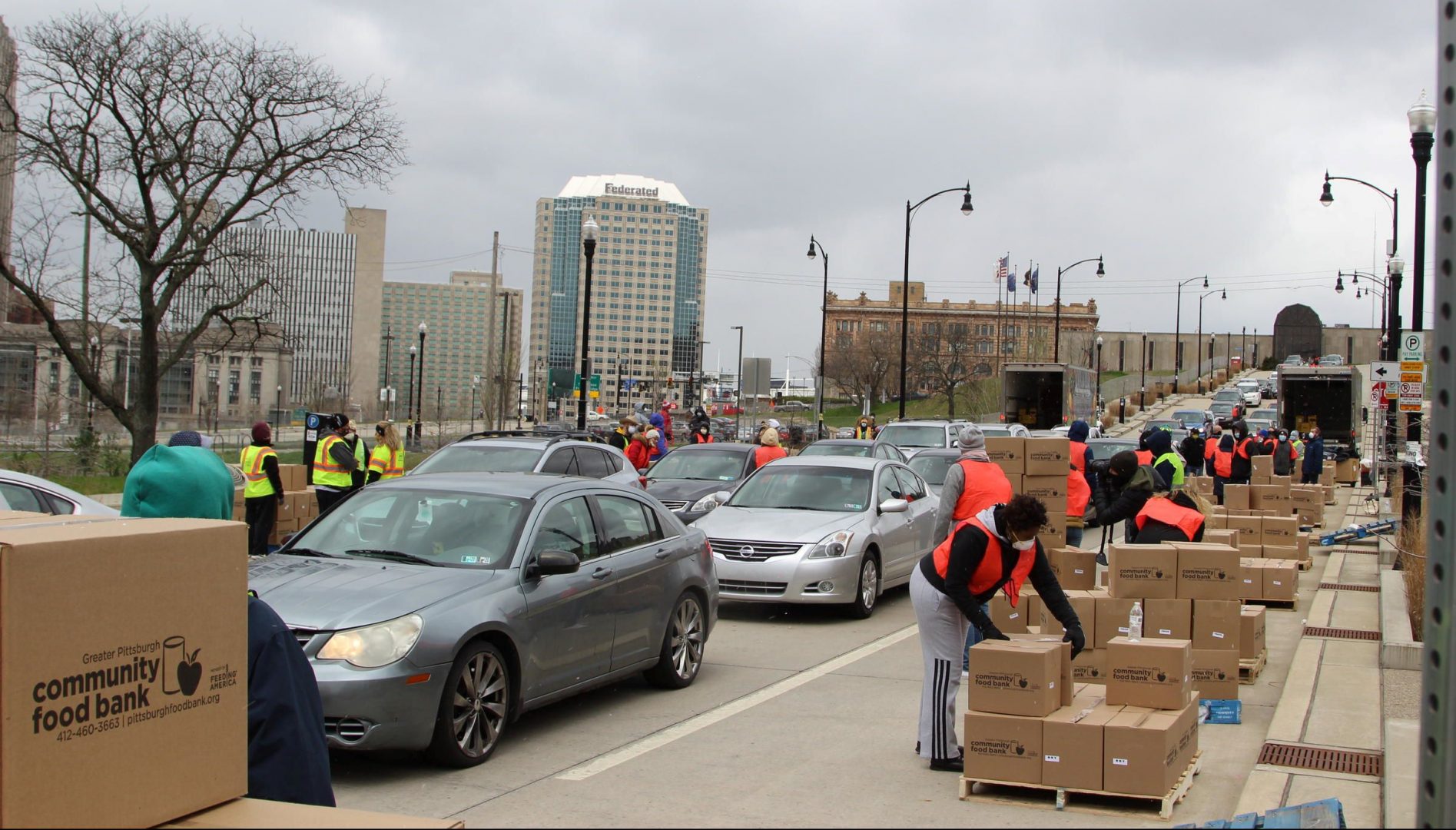 Volunteers distribute boxes of food to a long line of people at an event on April 10, 2020.