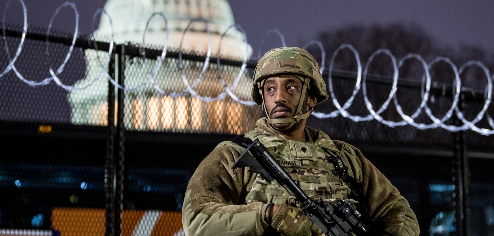 A member of the Virginia National Guard stands outside the razor wire fencing surrounding the U.S. Capitol on Friday. Up to 25,000 troops are expected by Inauguration Day.