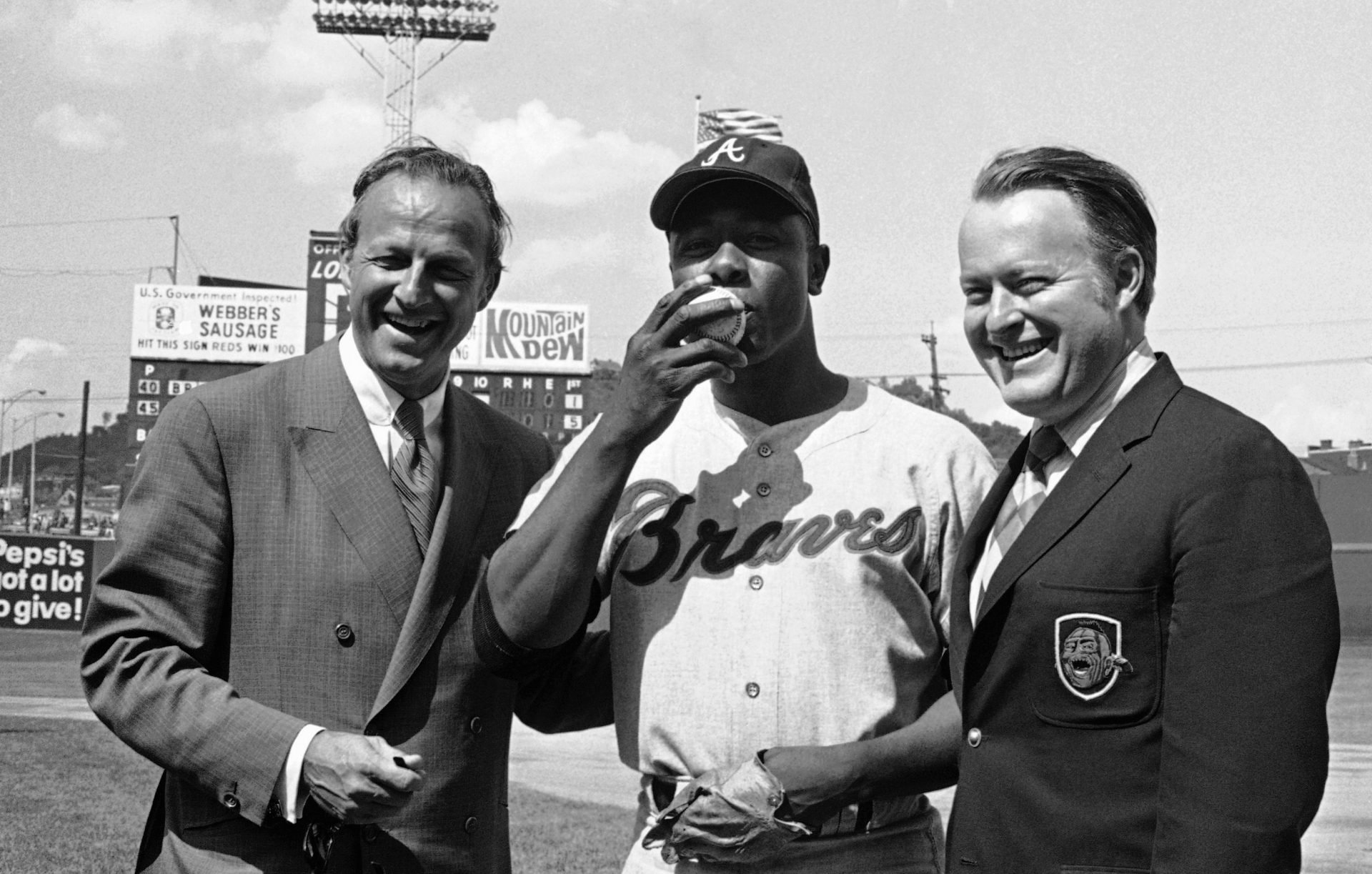 In this May 17, 1970, file photo Atlanta Braves' Hank Aaron, center, poses for photos after getting his 3,000th career hits during a baseball game against the Cincinnati Reds in Cincinnati. At left is Hall of Famer Stan Musial who was the last man to accomplish the feat, hitting his 3,000th in 1958. At right is Bill Bartholomay, owner of the Braves. Hank Aaron, who endured racist threats with stoic dignity during his pursuit of Babe Ruth but went on to break the career home run record in the pre-steroids era, died early Friday, Jan. 22, 2021. He was 86. The Atlanta Braves said Aaron died peacefully in his sleep. No cause of death was given.